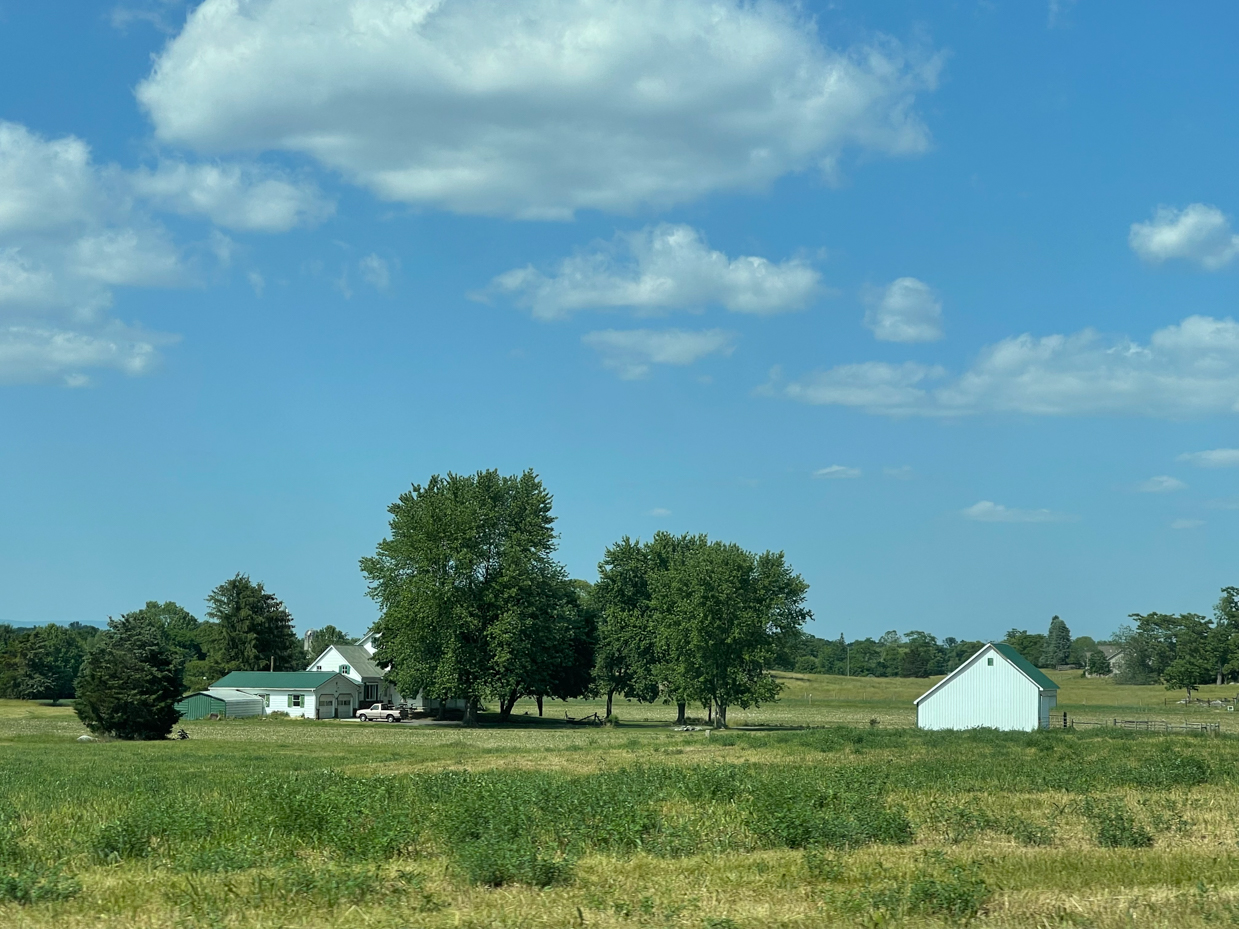 farmhouse-and-building-with-trees-and-clouds