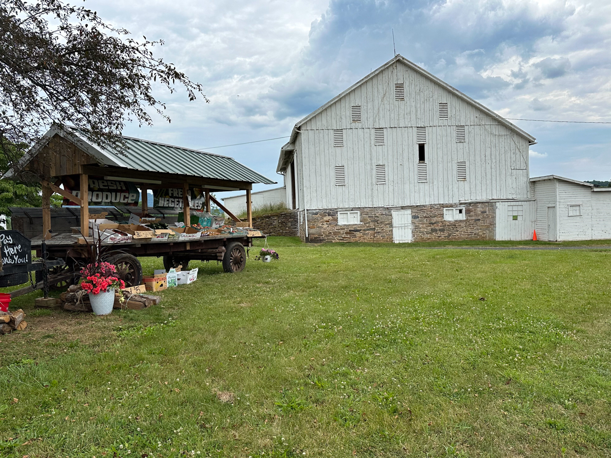 farm-stand-produce-wagon-white-barn-stone-foundation-cloudy-sky