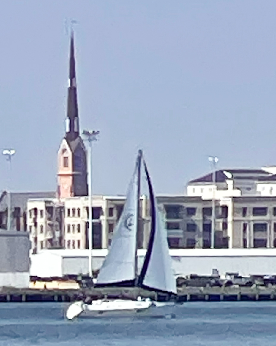 sailboat-with-a-cityscape-and-church-steeple-in-the-background-on-a-clear-day