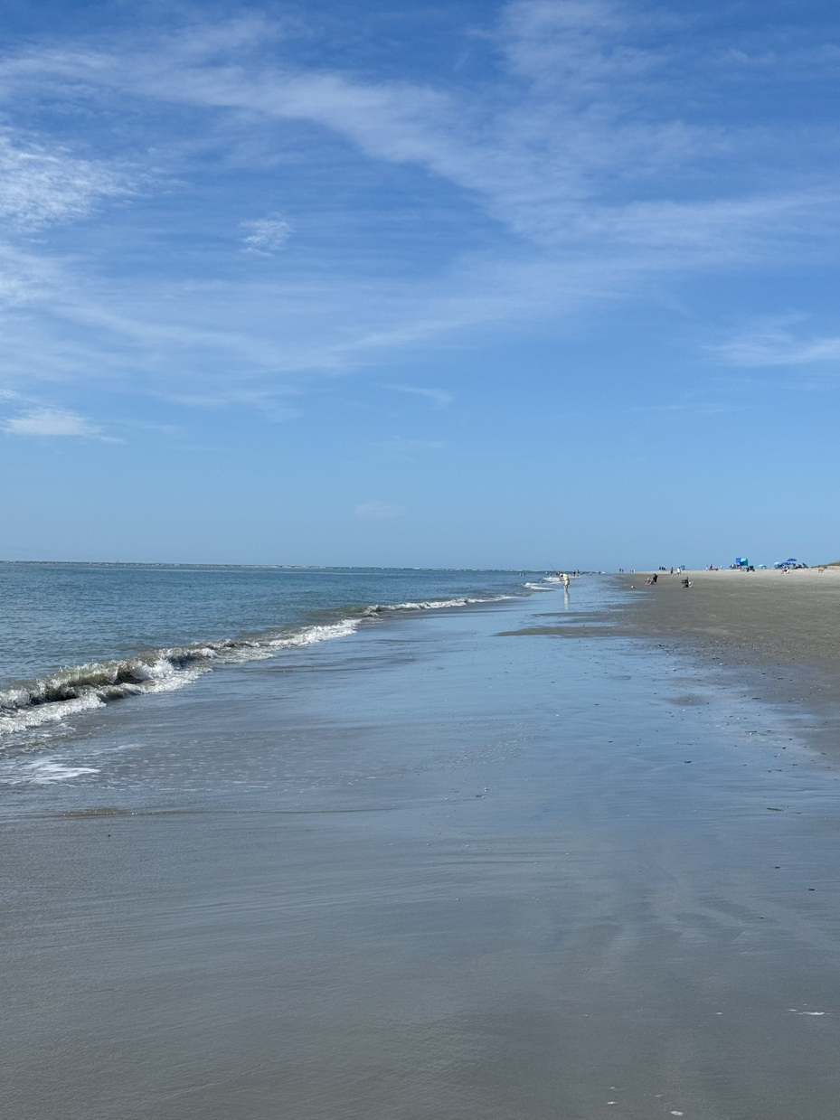 calm-ocean-waves-gently-lapping-at-a-wide-empty-sandy-beach-under-a-clear-blue-sky