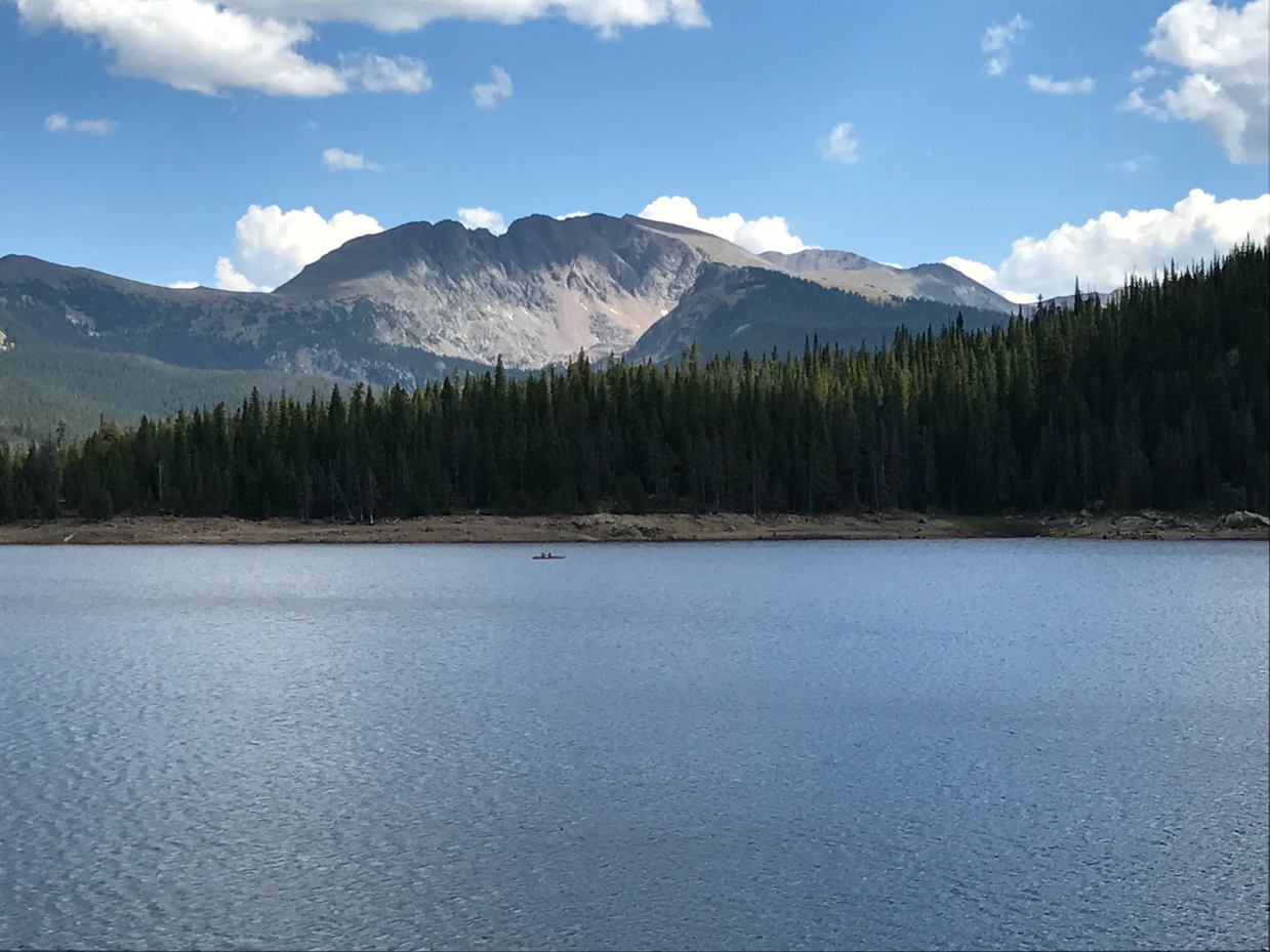 secluded-alpine-lake-with-pine-forest-snow-capped-peaks-and-lone-canoe