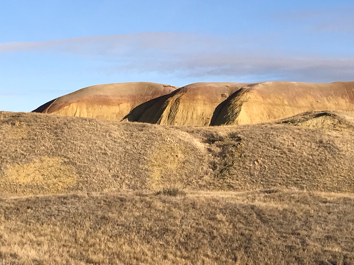 colorful-eroded-hills-in-badlands-national-park-with-golden-grassland-royalty-free-landscape-reference-photo-for-desert-geology-layered-terrain-and-wilderness-photography