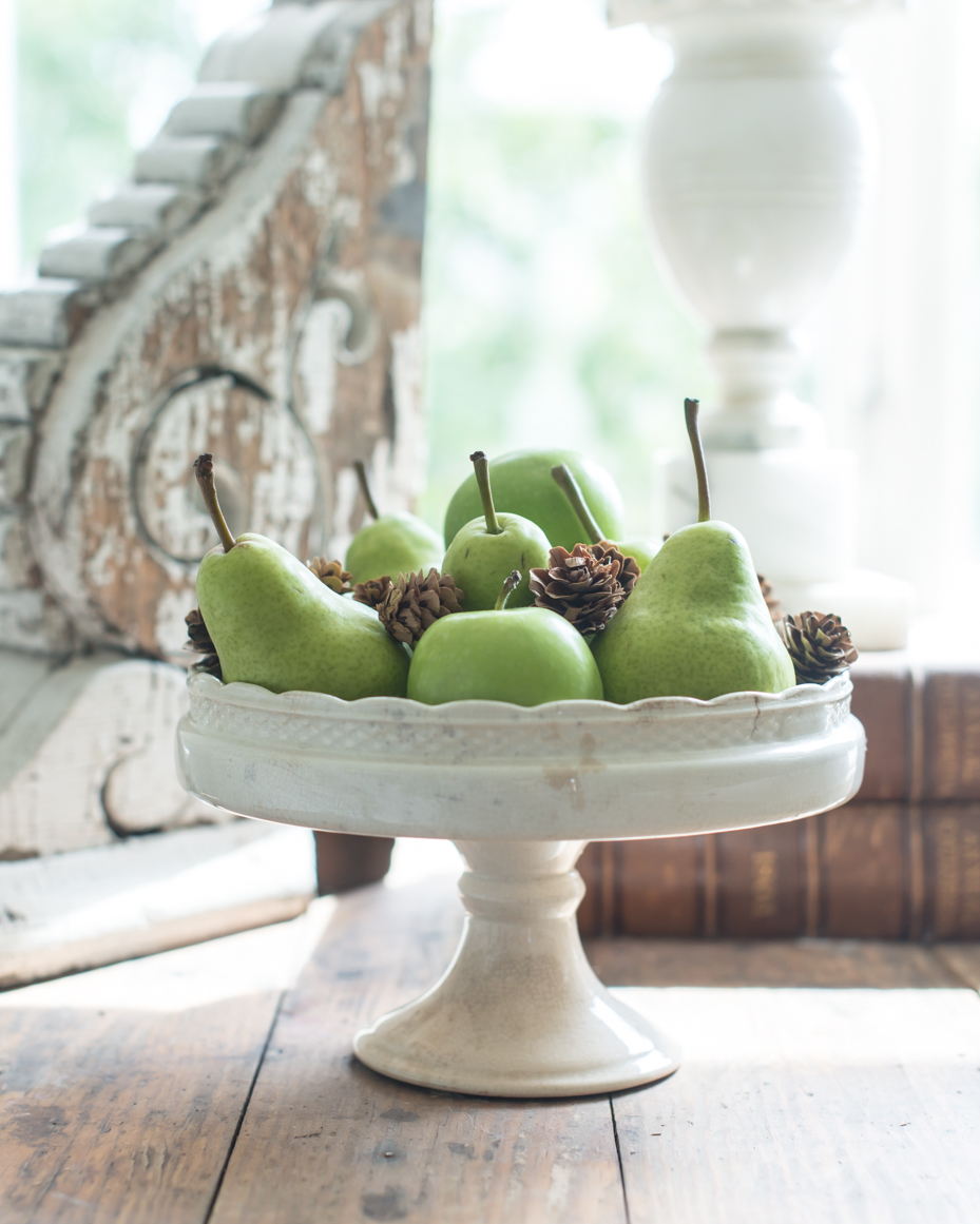 fresh-green-pears-and-pine-cones-on-rustic-pedestal-stand-with-antique-decor-royalty-free-reference-photo