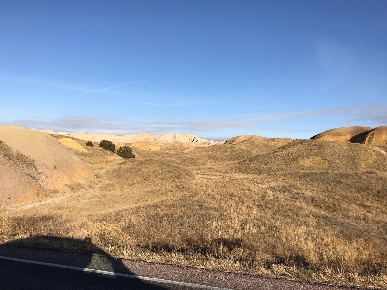 golden-hills-and-colorful-badlands-formations-under-clear-sky-in-open-grassland-royalty-free-nature-landscape-reference-photo-for-desert-geology-eroded-terrain-and-wilderness-photography