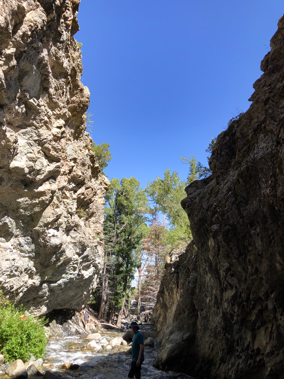 hiker-walking-through-rocky-canyon-stream-nature-adventure-photography-with-clear-blue-sky