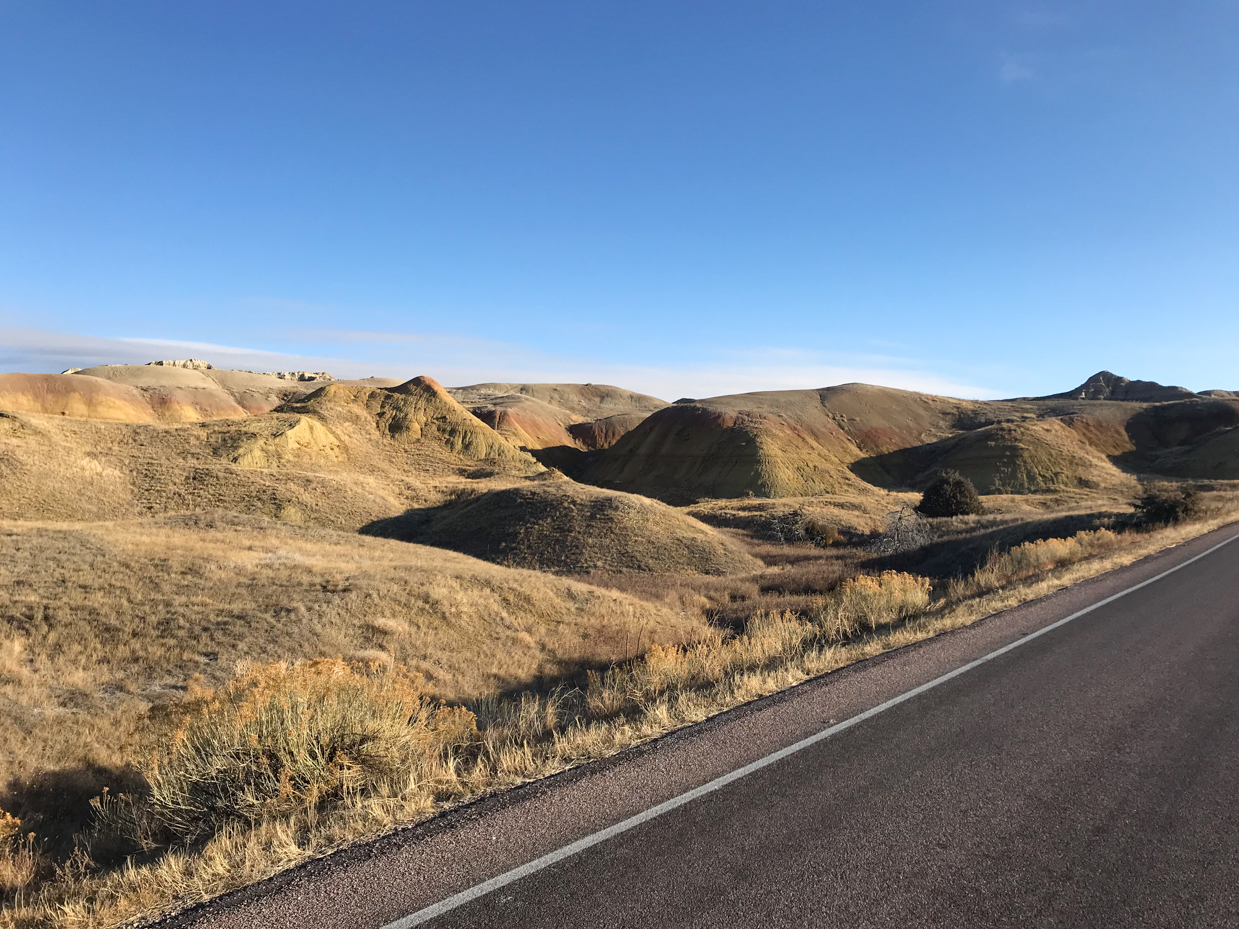 open-road-through-colorful-rolling-hills-and-grasslands-in-badlands-national-park-royalty-free-landscape-reference-photo-for-scenic-drives-desert-terrain-and-wilderness-exploration