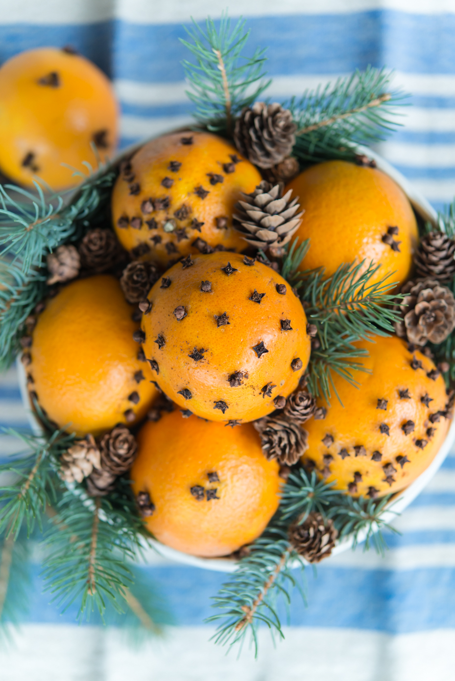 oranges-decorated-with-cloves-and-pine-cones-in-festive-arrangement-on-blue-striped-fabric-royalty-free-reference-photo