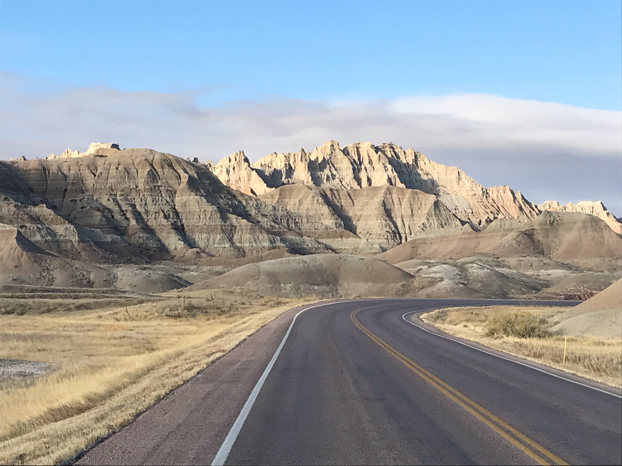 scenic-road-curving-through-badlands-national-park-with-striking-rock-formations-and-open-desert-landscape-royalty-free-nature-and-travel-photography-reference-for-rugged-terrain-and-scenic-drives