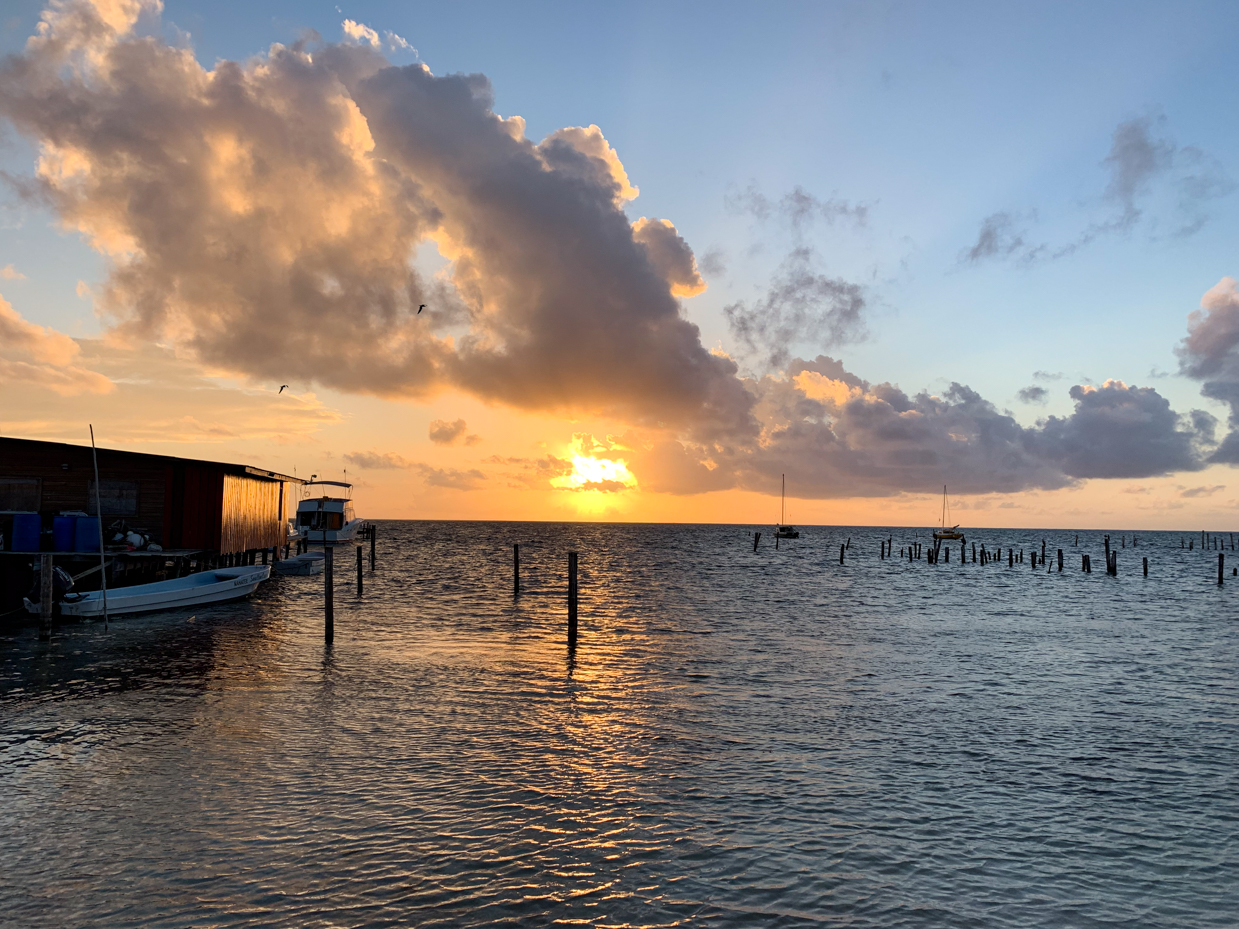 sunset-over-calm-ocean-with-boats-and-dock-under-dramatic-clouds-royalty-free-seascape-reference-photo-for-coastal-views-scenic-sunsets-and-maritime-photography