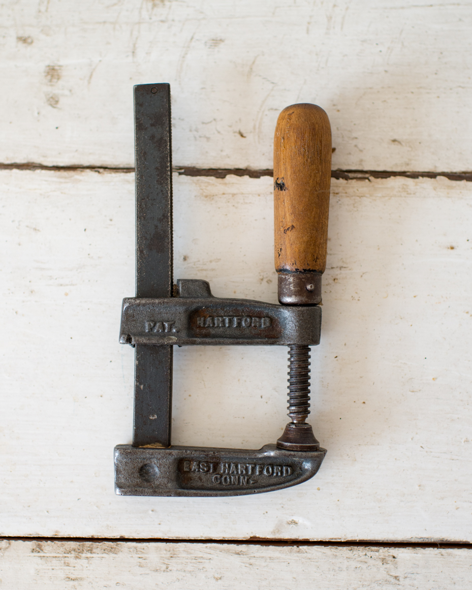 vintage-metal-clamp-with-wooden-handle-on-rustic-white-surface-royalty-free-reference-photo