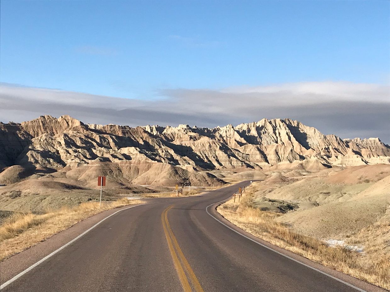 winding-road-through-badlands-national-park-with-striking-mountainous-rock-formations-and-clear-blue-sky-royalty-free-landscape-and-travel-reference-photo-for-rugged-terrain-scenic-drives-and-wild