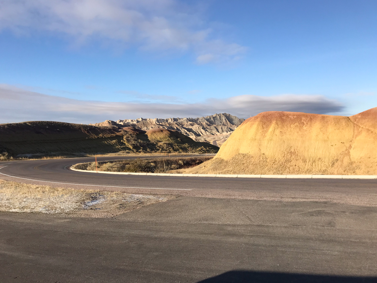 winding-road-through-golden-hills-and-rocky-badlands-formations-in-clear-morning-light-royalty-free-landscape-reference-photo-for-scenic-drives-desert-terrain-and-wilderness-exploration