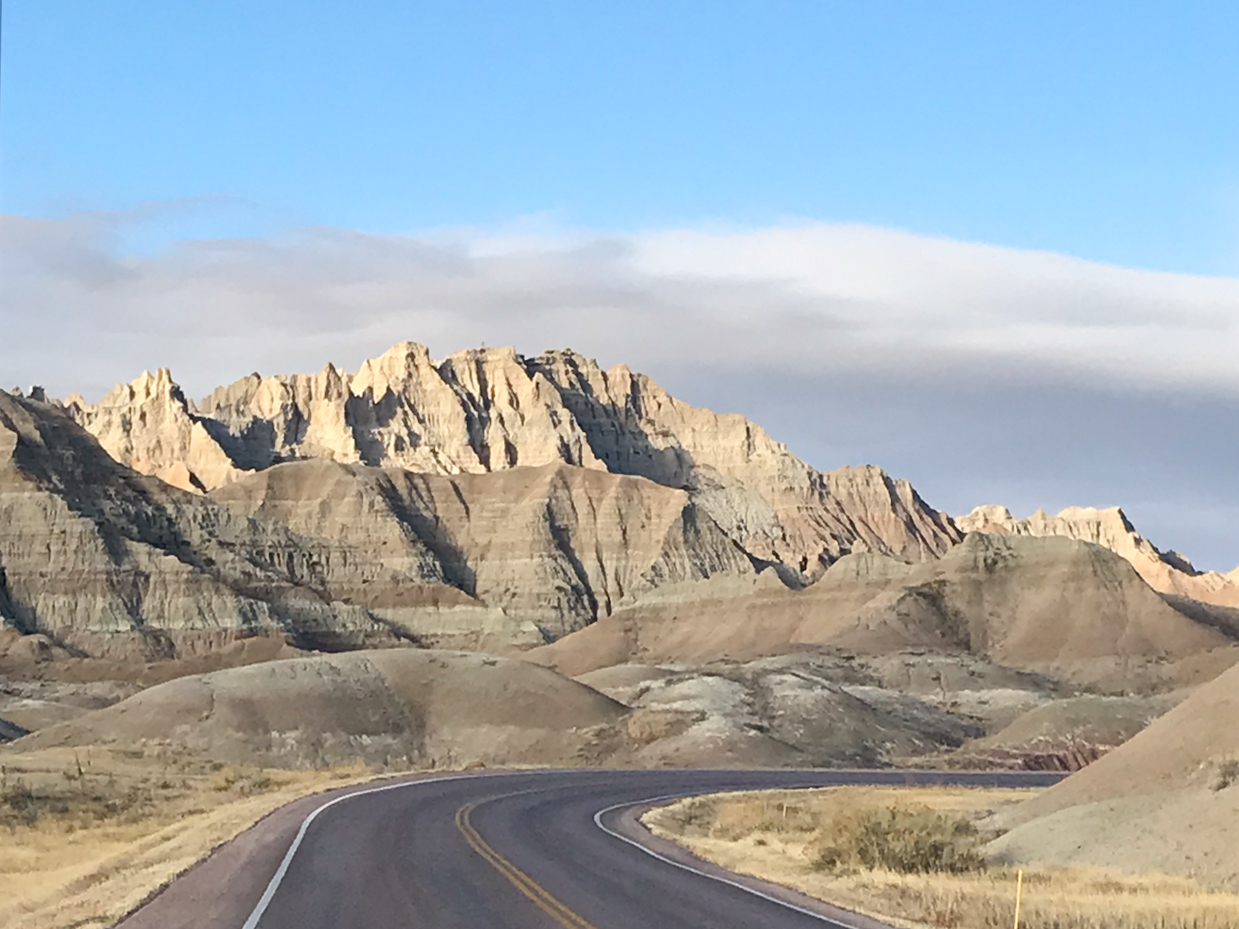 winding-road-through-majestic-badlands-with-jagged-peaks-and-desert-hills-royalty-free-landscape-reference-photo-for-scenic-drives-rugged-terrain-and-mountain-formations-photography