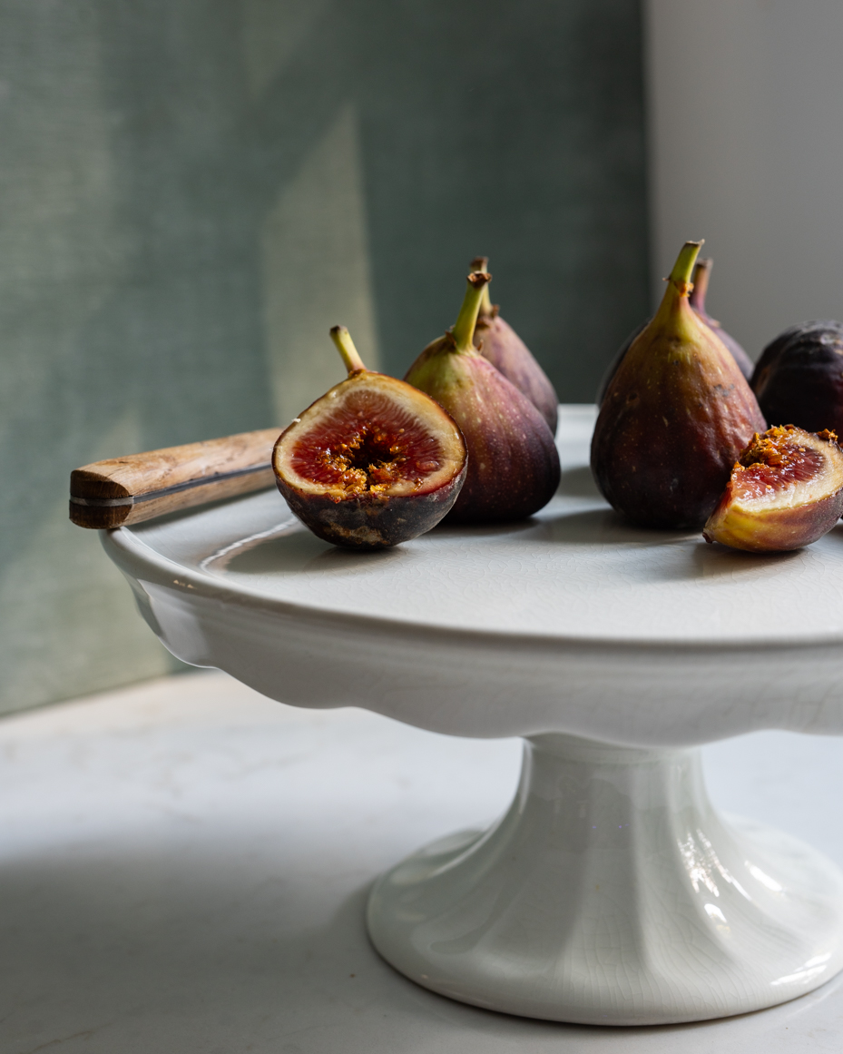 close-up-of-fresh-figs-on-cake-stand-with-rustic-knife-and-natural-light