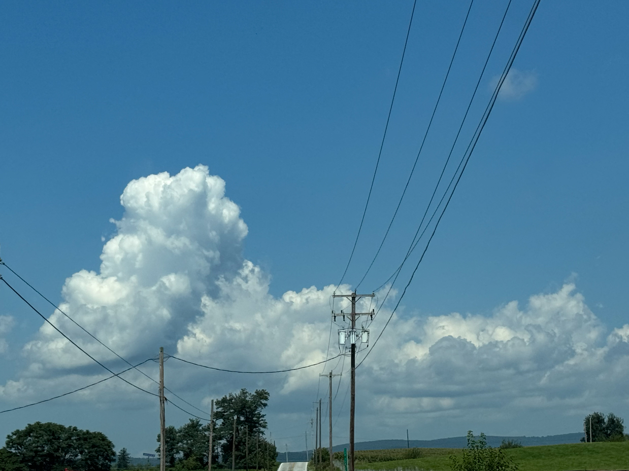 country-road-with-power-lines-and-large-cumulus-clouds-in-blue-sky