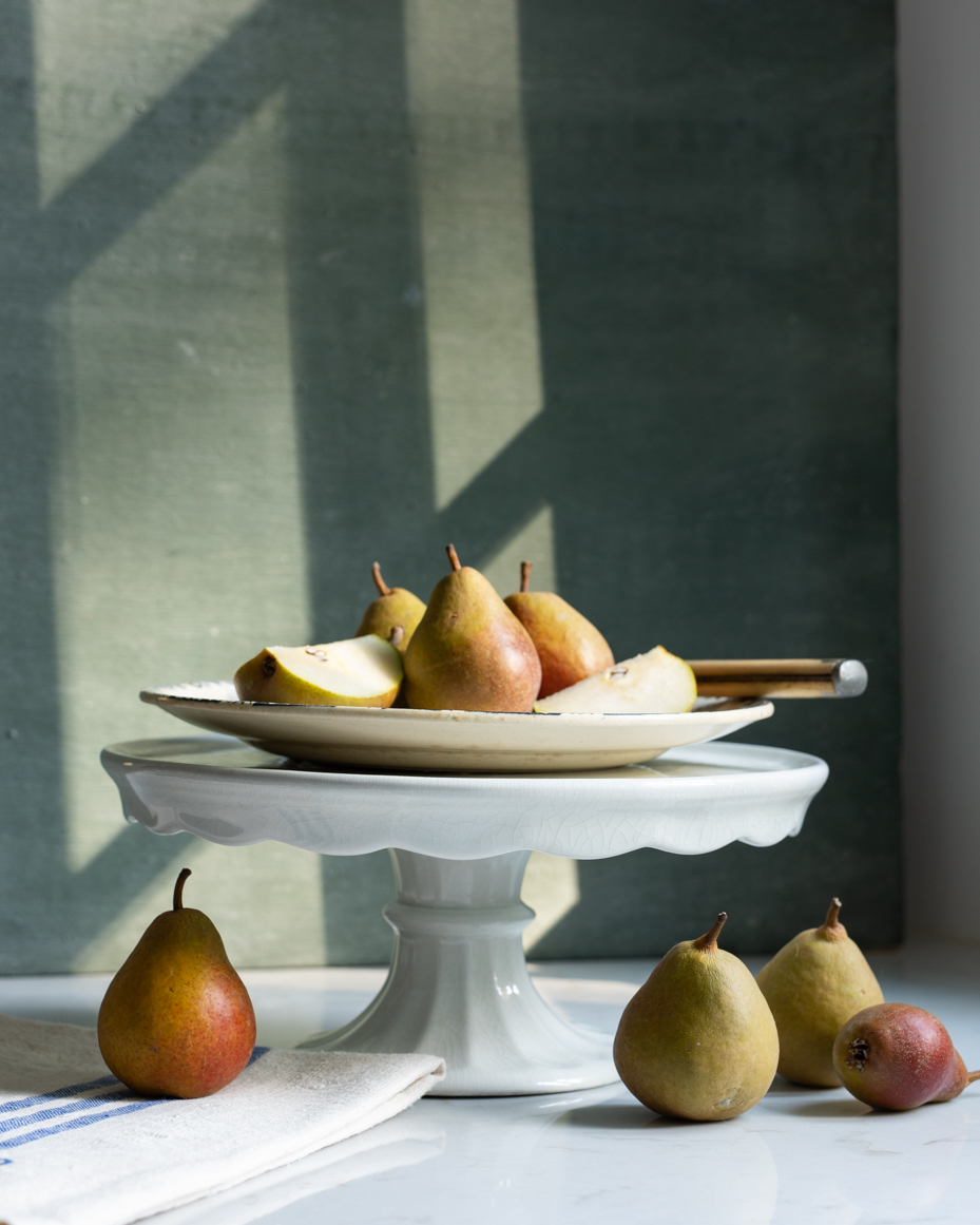 elegant-still-life-of-pears-on-cake-stand-with-rustic-linen-and-sunlight