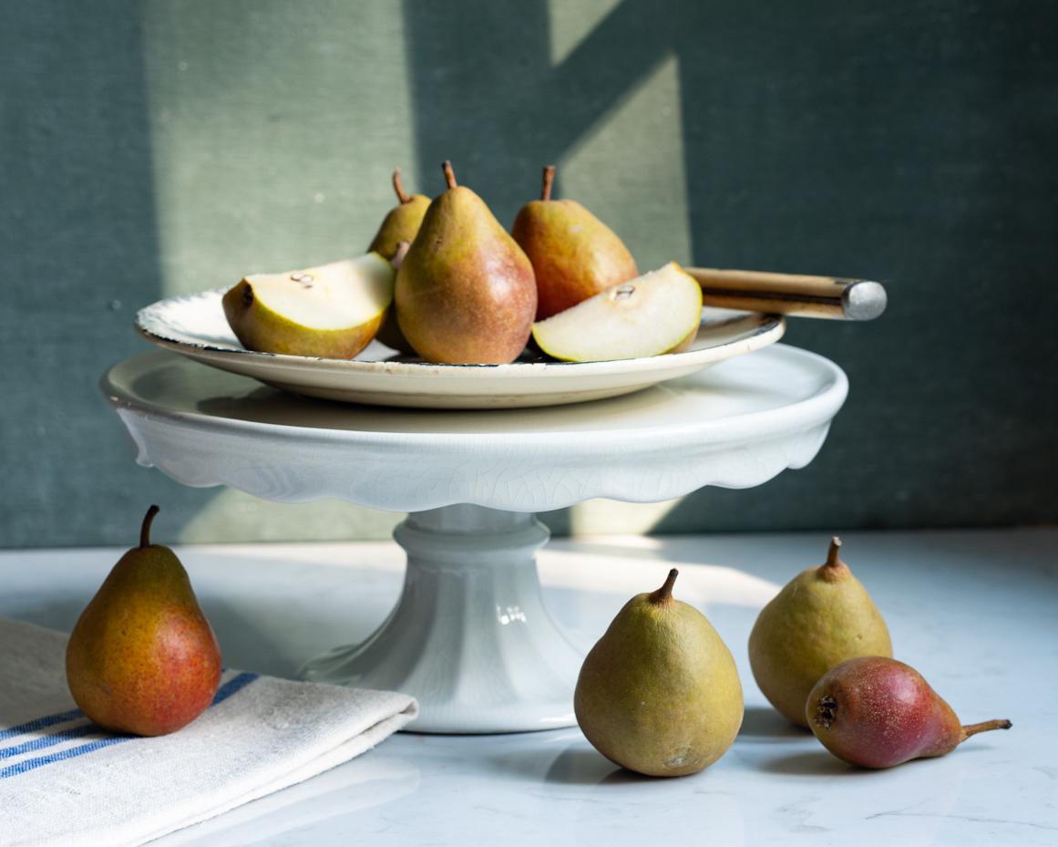 pears-on-cake-stand-with-linen-in-natural-light-rustic-still-life-decor