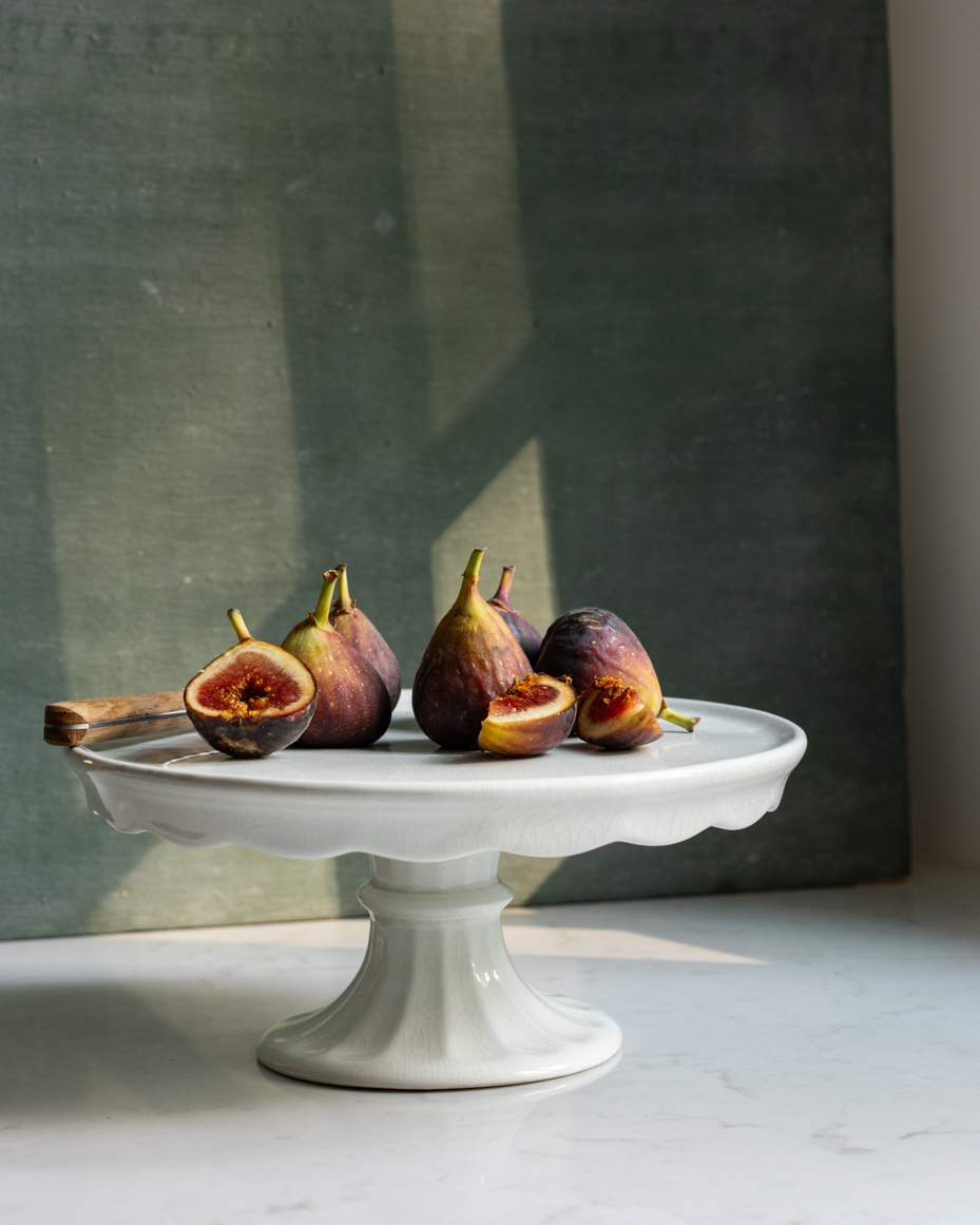 ripe-figs-on-ceramic-cake-stand-with-sunlit-background-rustic-still-life