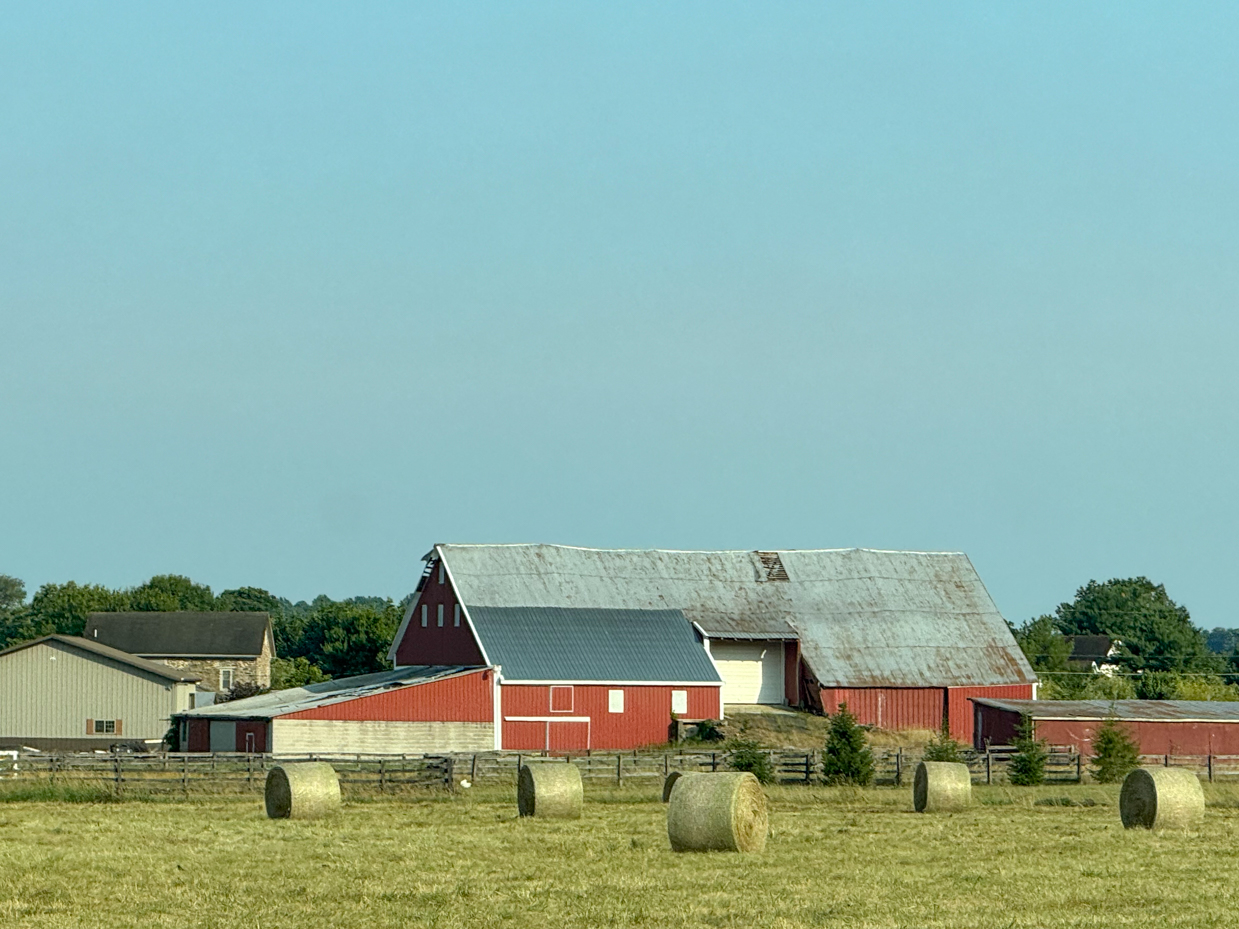 rustic-red-barn-with-hay-bales-in-a-countryside-farm-field