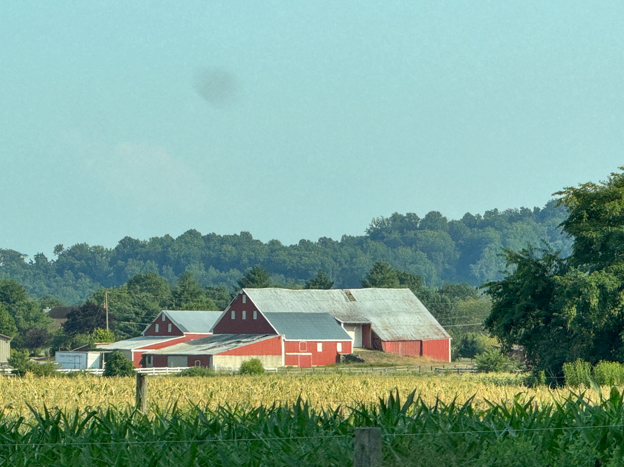 scenic-red-barn-in-a-countryside-cornfield-with-rolling-hills-in-the-background