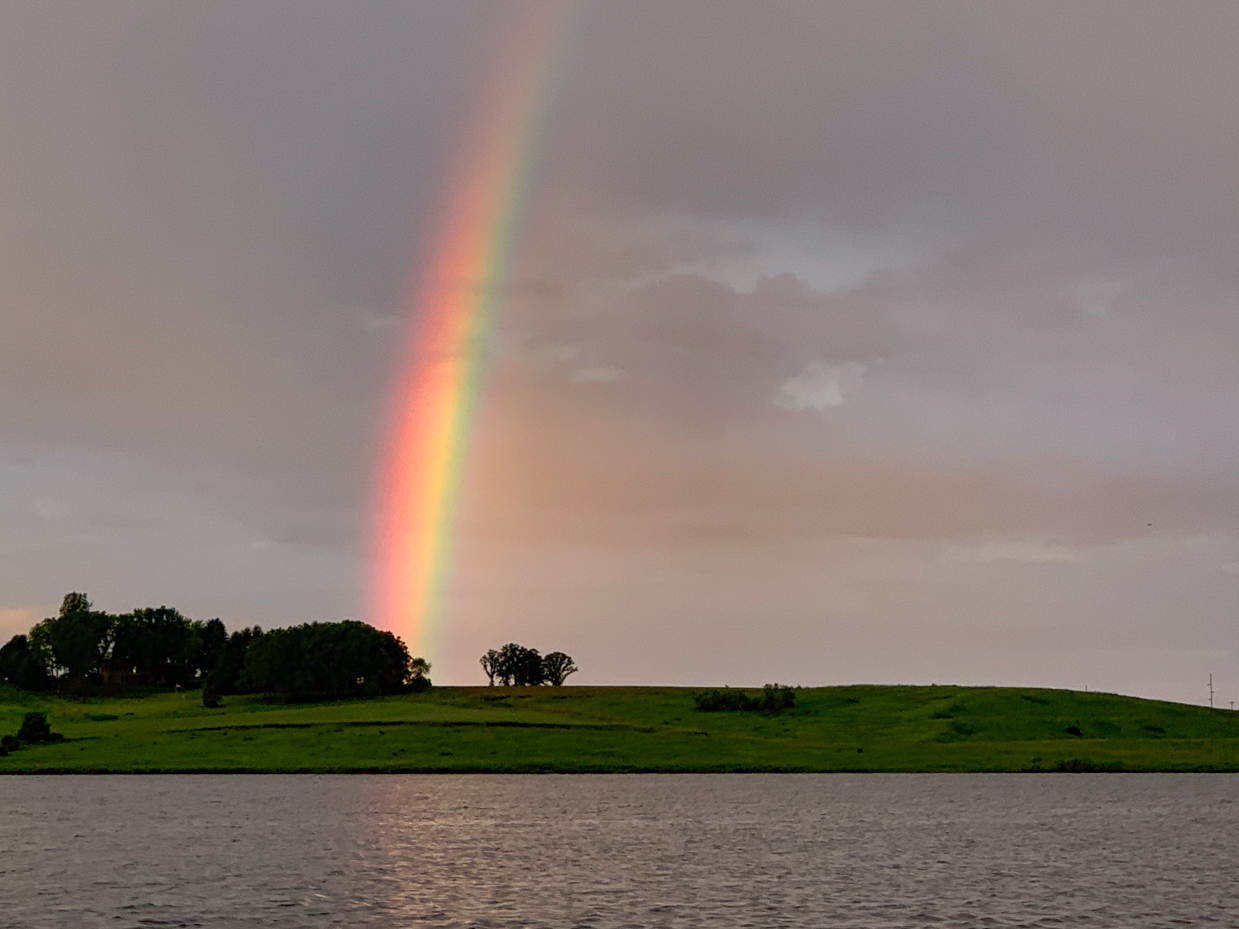 Vibrant Rainbow Over Calm Waters and Green Hills – Capturing Nature’s ...