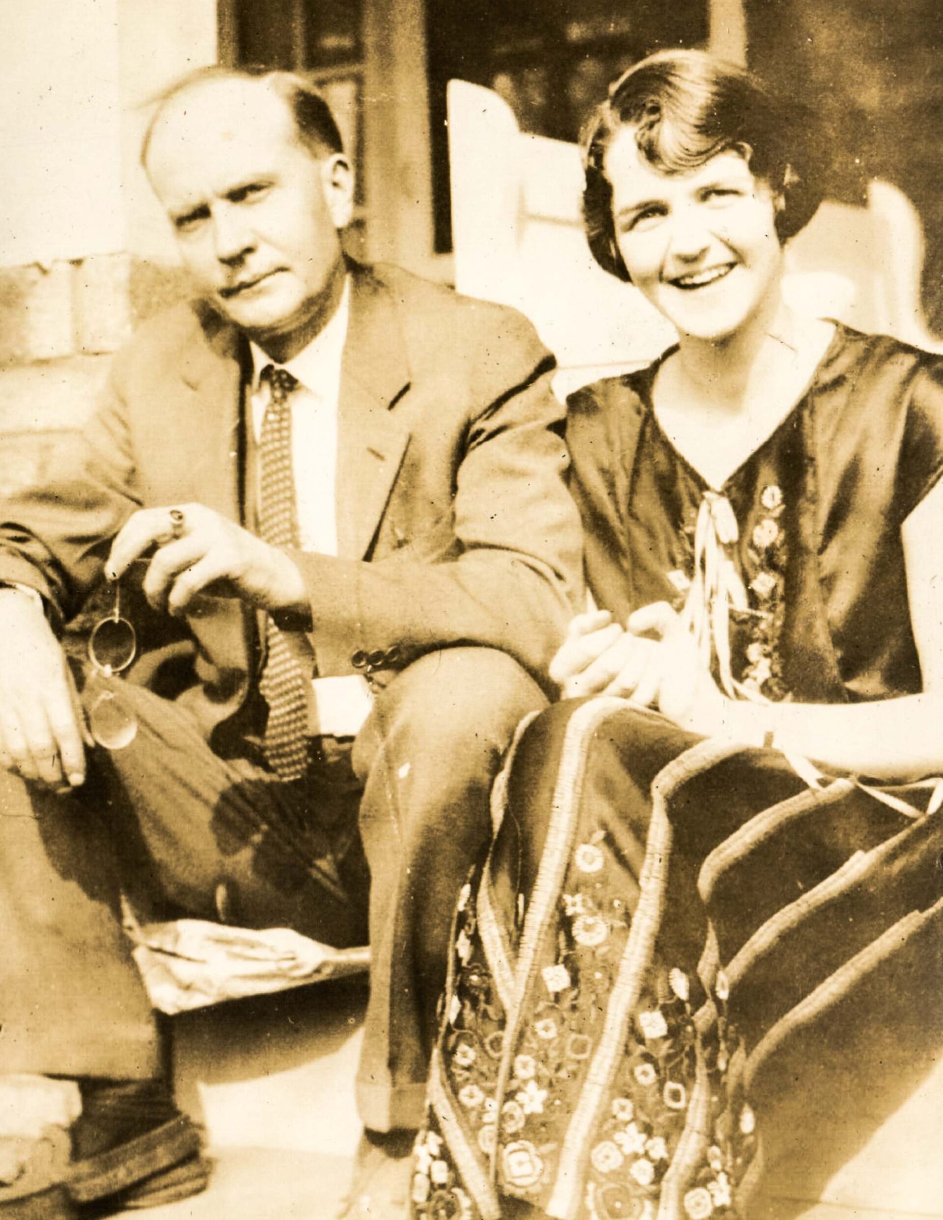 1920s-vintage-portrait-of-smiling-couple-sitting-outdoors