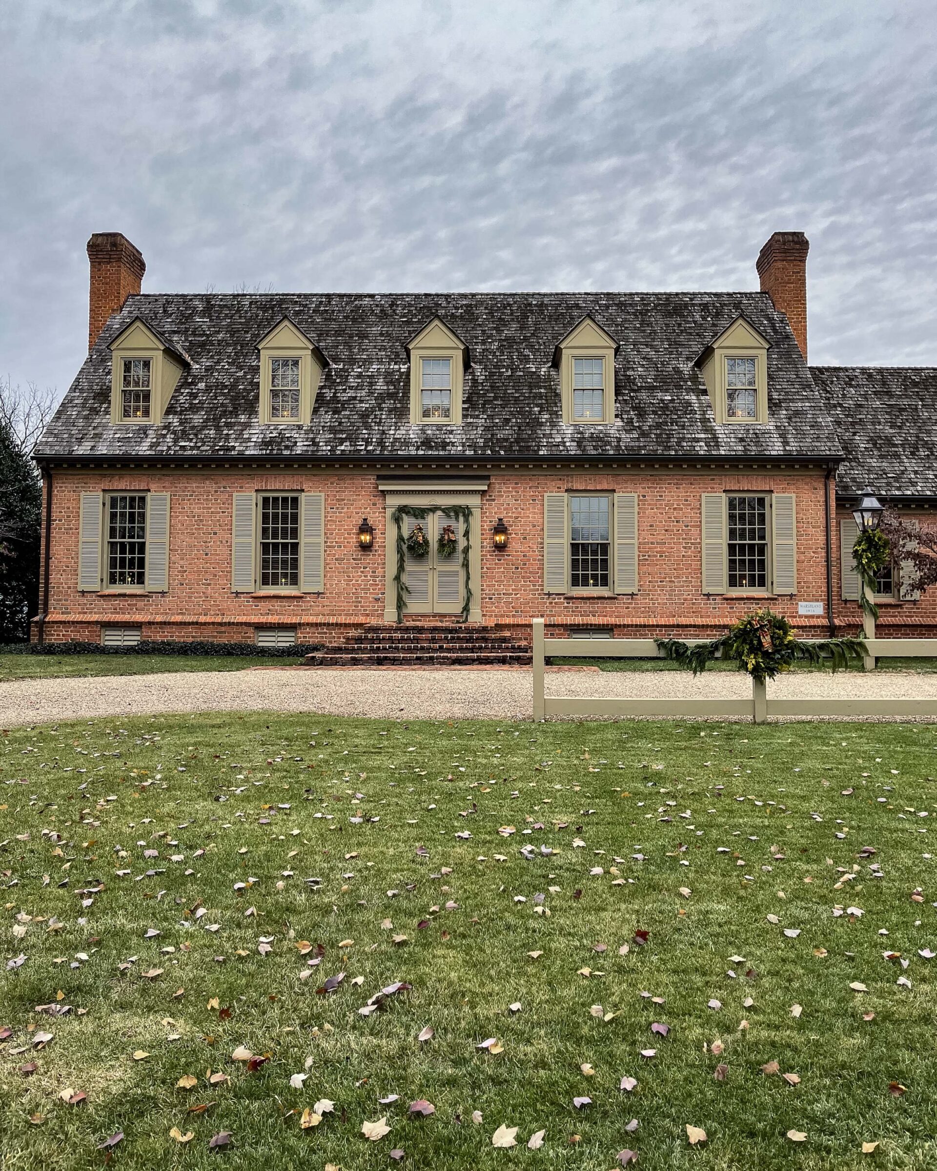 classic-colonial-brick-house-with-dormer-windows-and-greenery-decor-winter-exterior