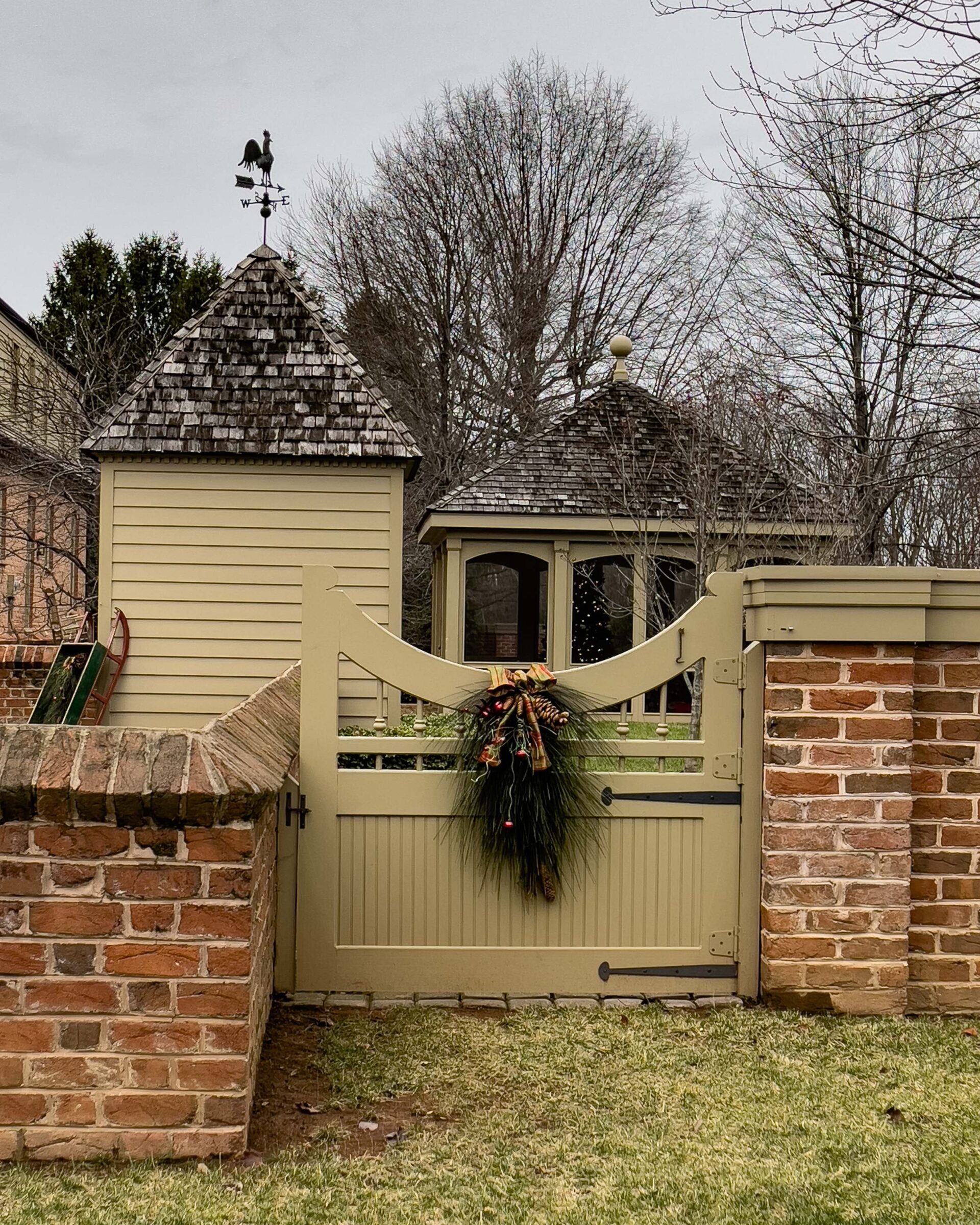 colonial-style-garden-gate-with-holiday-greenery-decor-and-weathervane