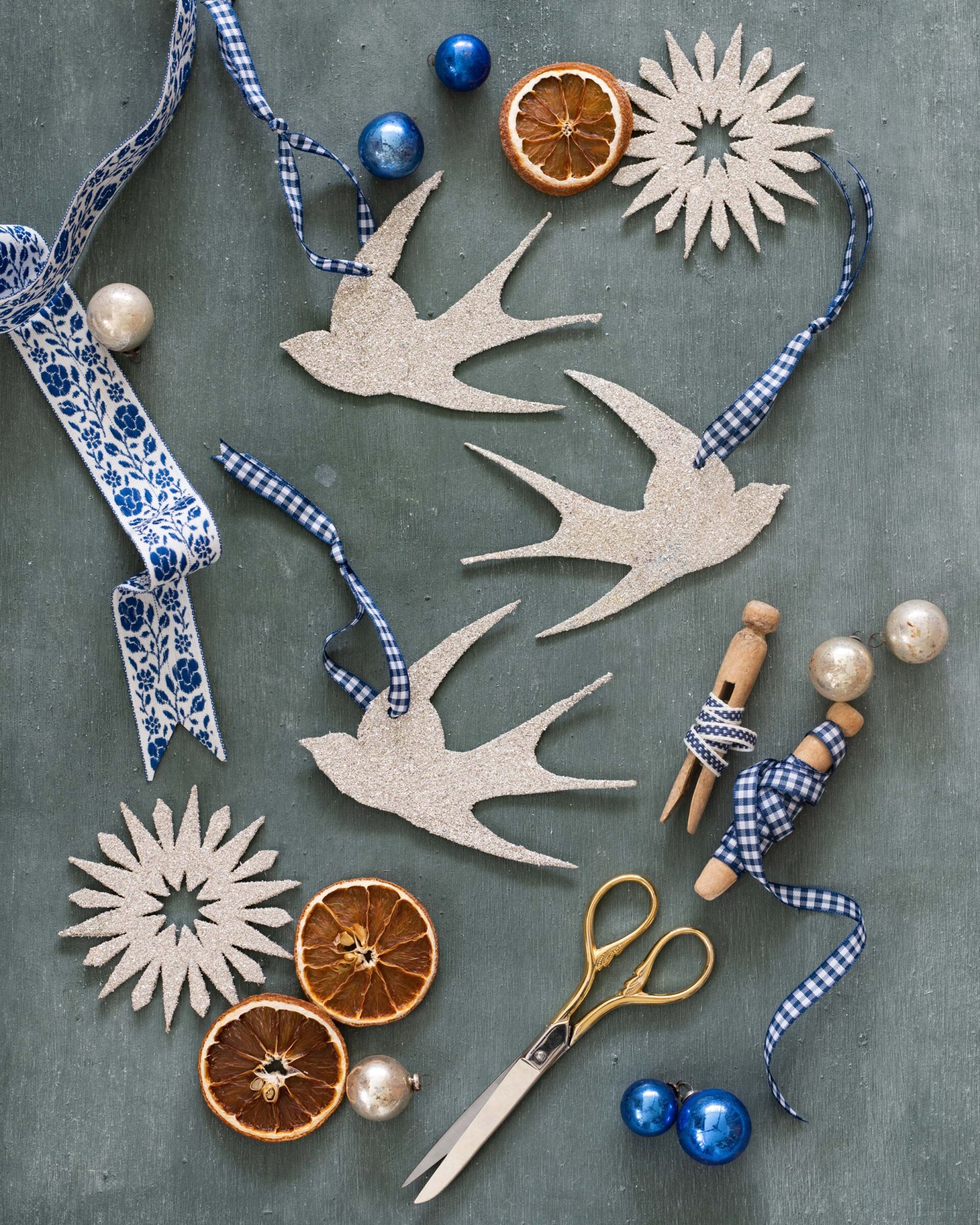 festive-holiday-crafting-with-gingham-ribbon-glittery-bird-ornaments-dried-orange-slices-and-vintage-scissors-on-sage-green-background