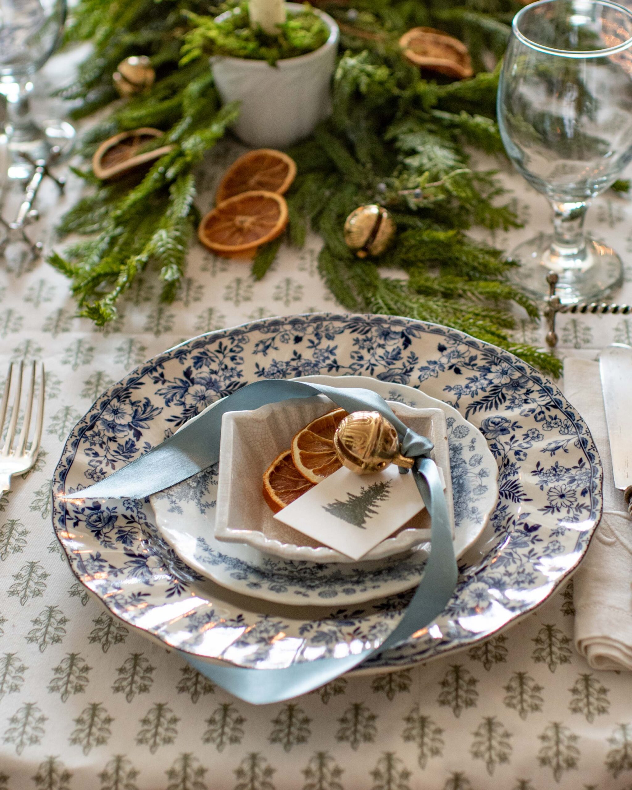 Festive Holiday Table Setting with Blue Floral China, Fresh Greenery, and Dried Orange Slices artist reference photo