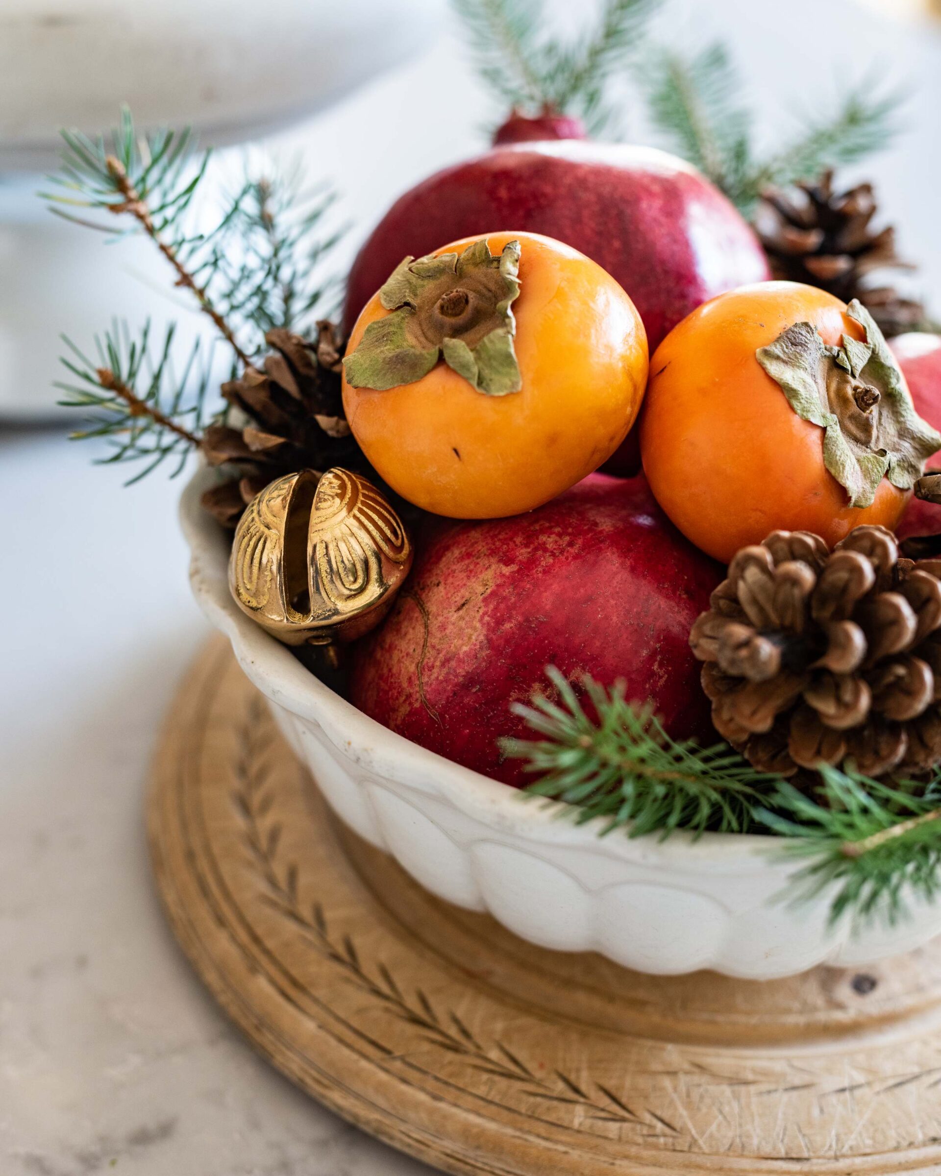 festive-holiday-fruit-bowl-with-pomegranates-and-persimmons-decorated-with-pinecones-and-evergreen-sprigs