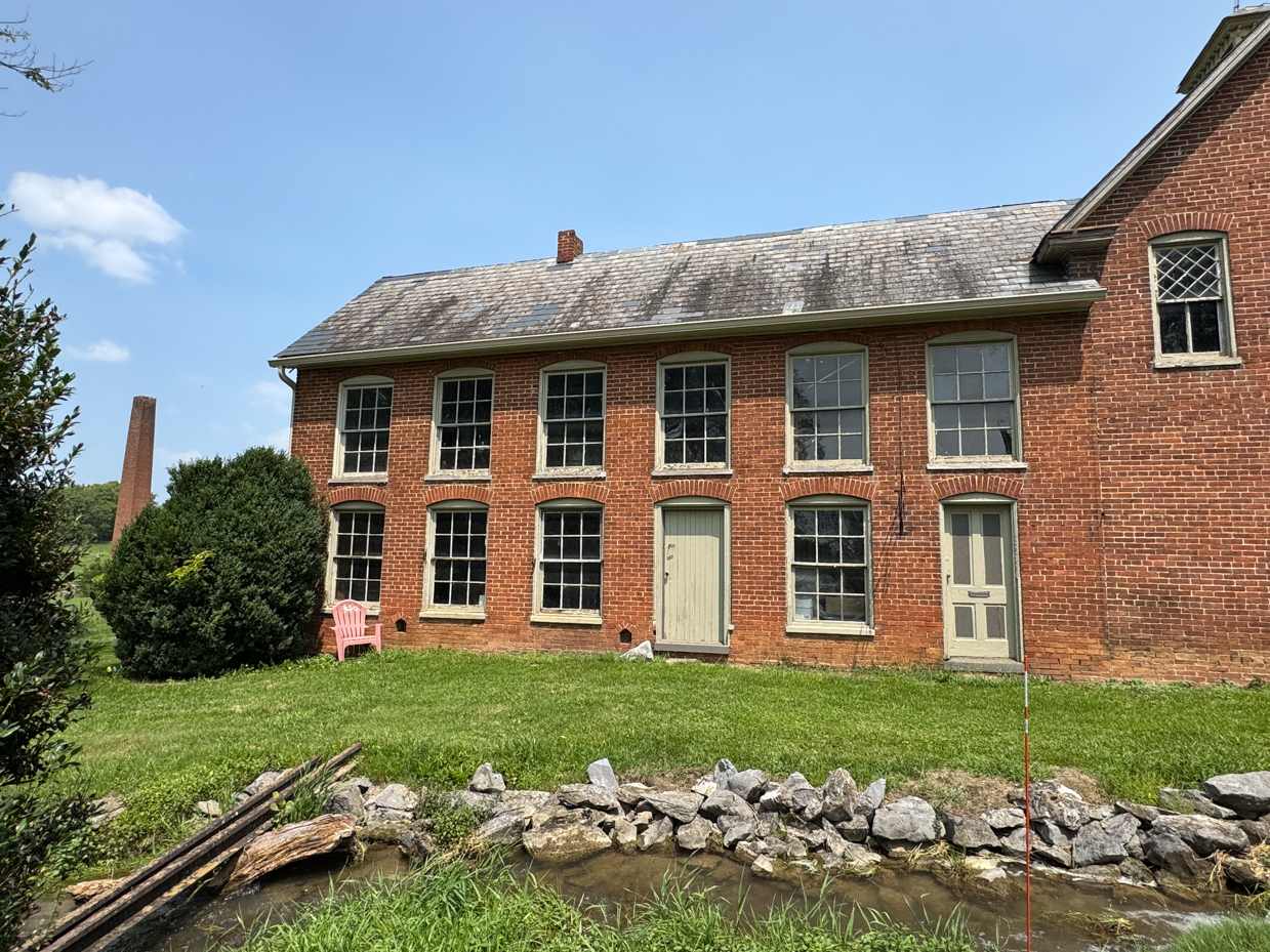 historic-brick-farmhouse-stream-stone-wall-rural-landscape