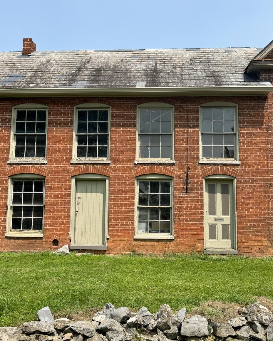 historic-brick-farmhouse-weathered-roof-windows-stone-wall