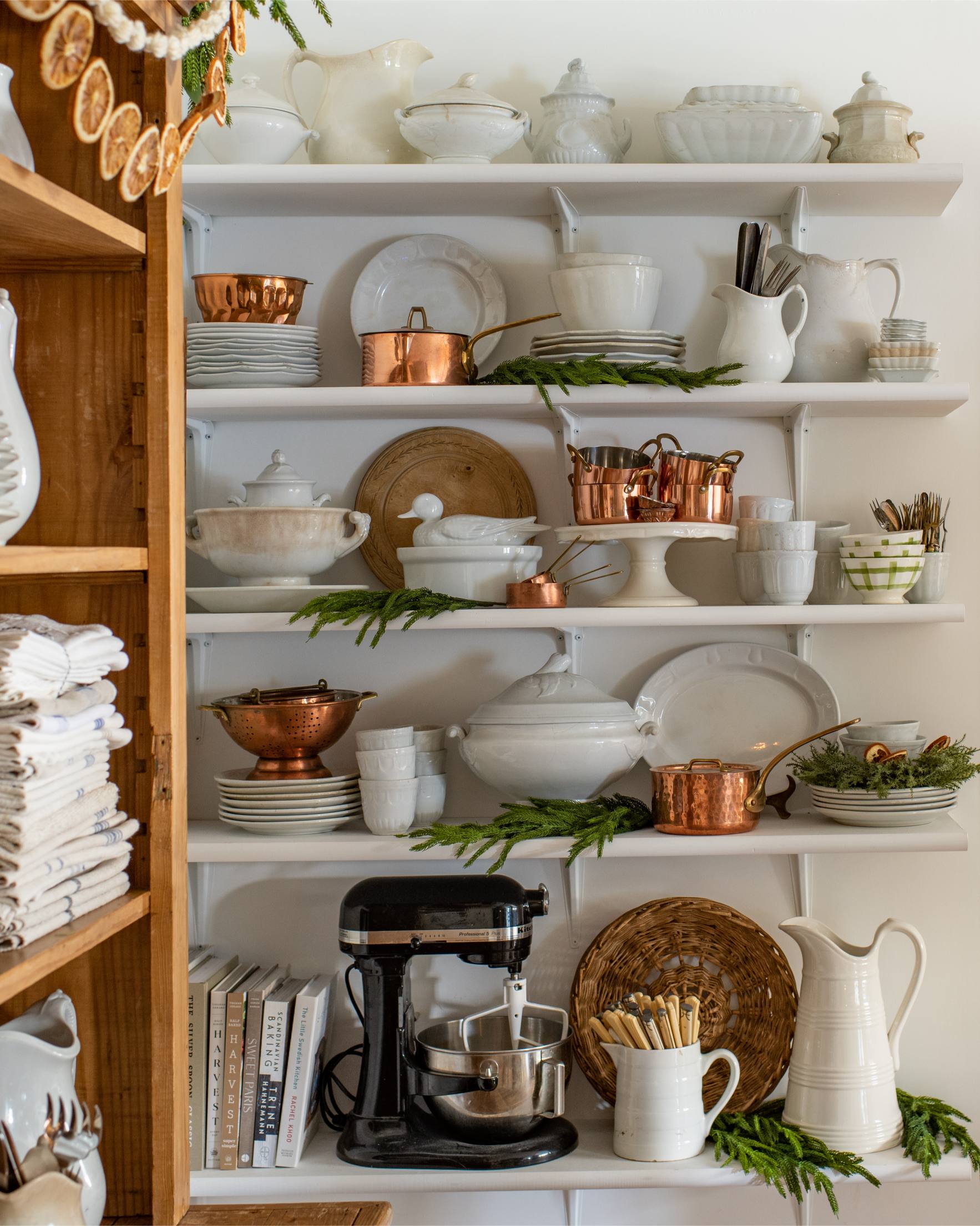 holiday-kitchen-shelf-styling-with-white-ceramics-copper-pots-greenery-candlelight-and-mini-gingerbread-houses