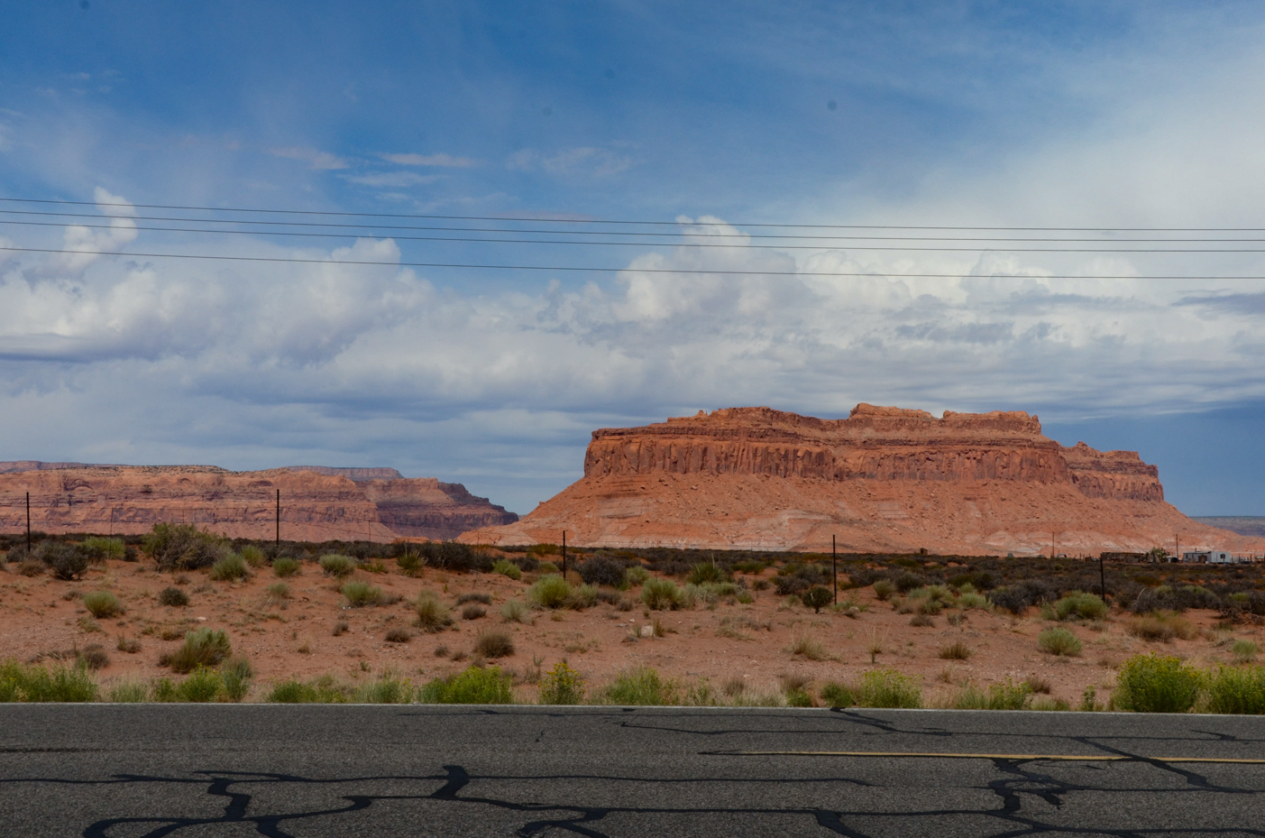 iconic-southwest-mesa-towering-over-cracked-desert-highway-under-wispy-clouds