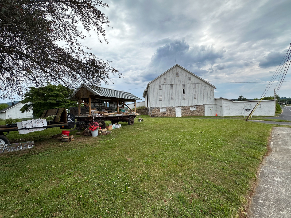 rural-farm-stand-white-barn-cloudy-sky-country-road-scenic-landscape