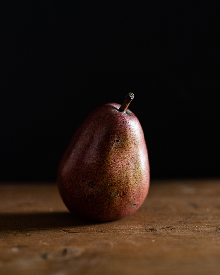 single-red-pear-on-rustic-wooden-surface-with-dark-background-minimalist-food-photography