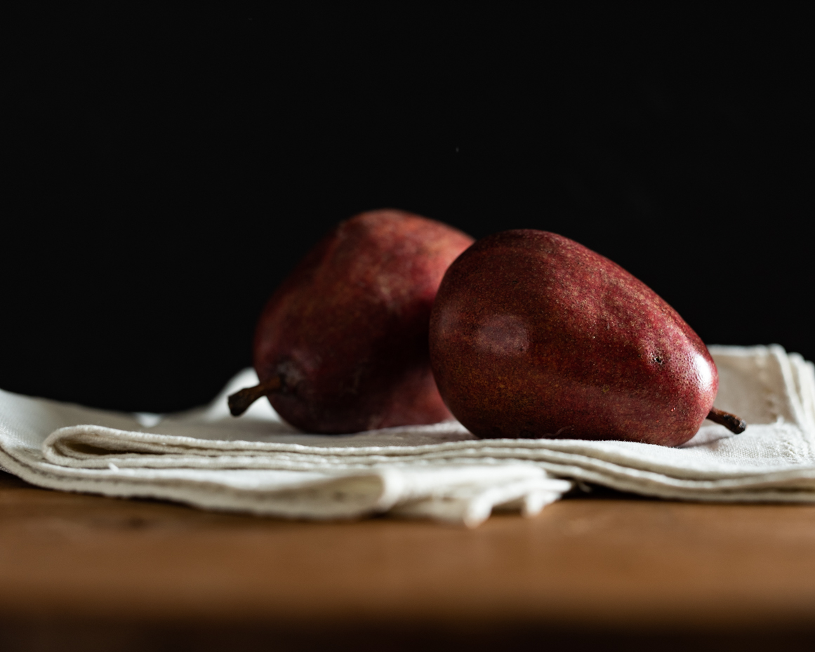 two-red-pears-resting-on-linen-napkins-minimalist-rustic-still-life-with-dark-background