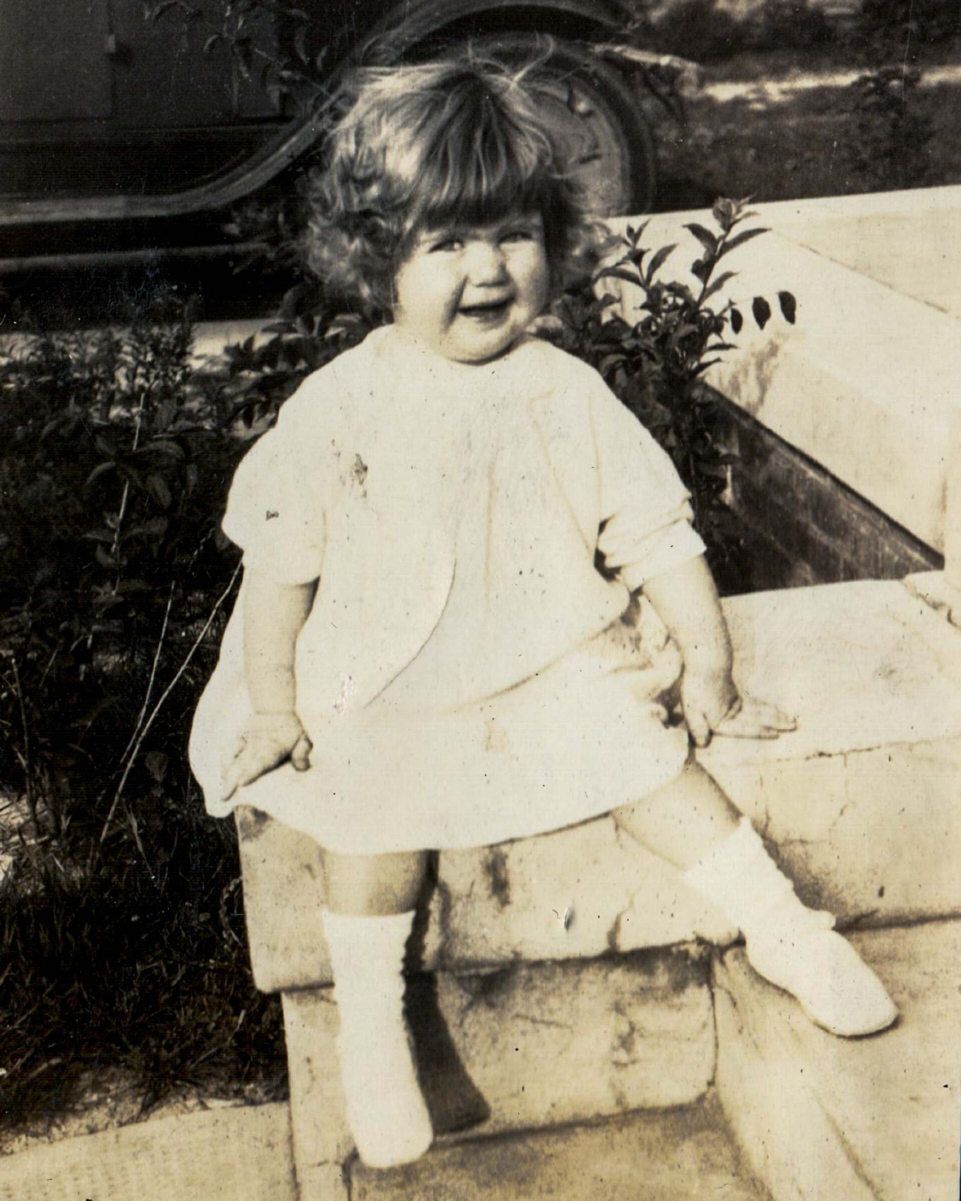 vintage-1920s-portrait-of-smiling-toddler-sitting-outdoors