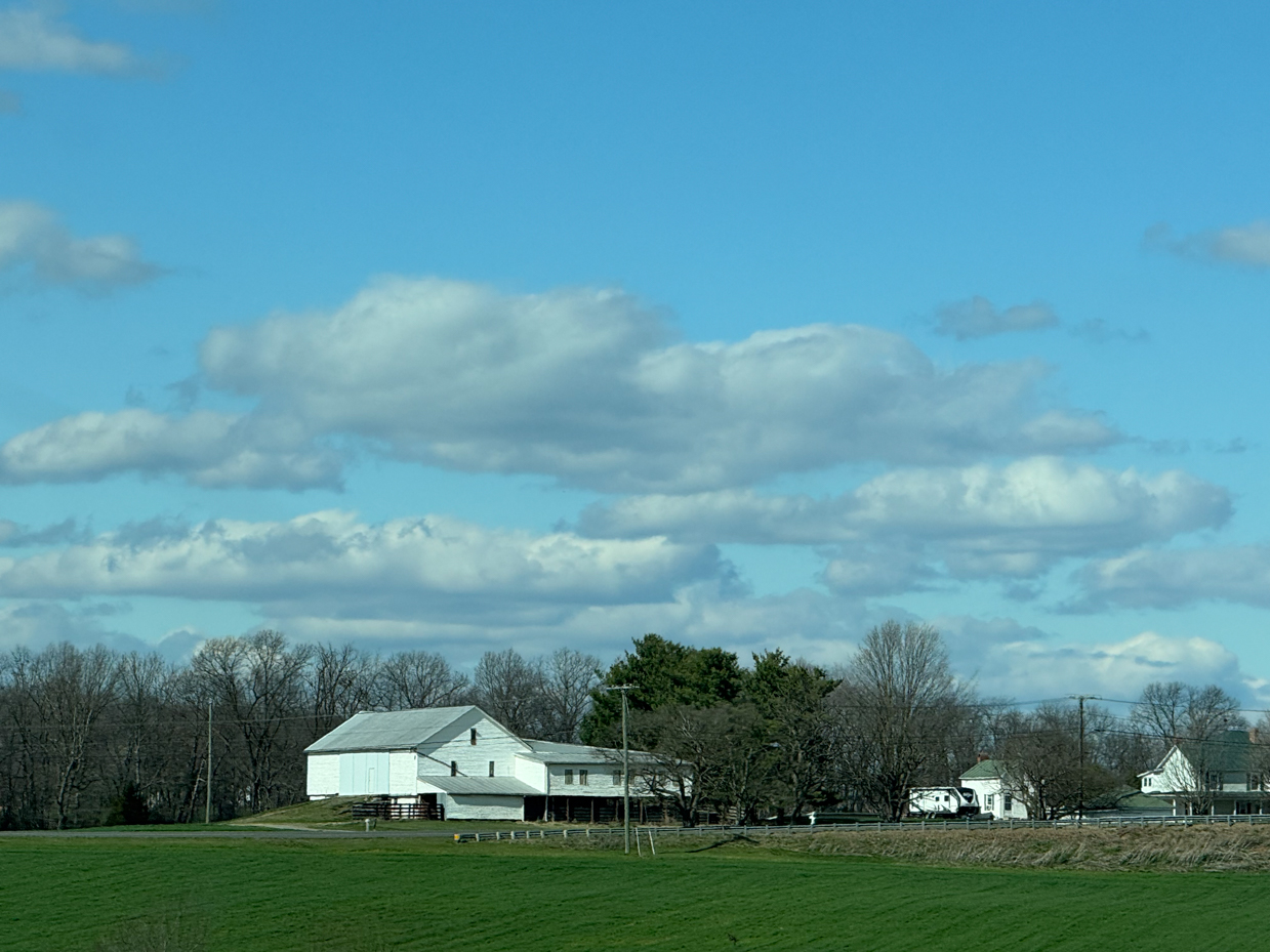 white-barn-green-field-cloudy-sky-rural-landscape