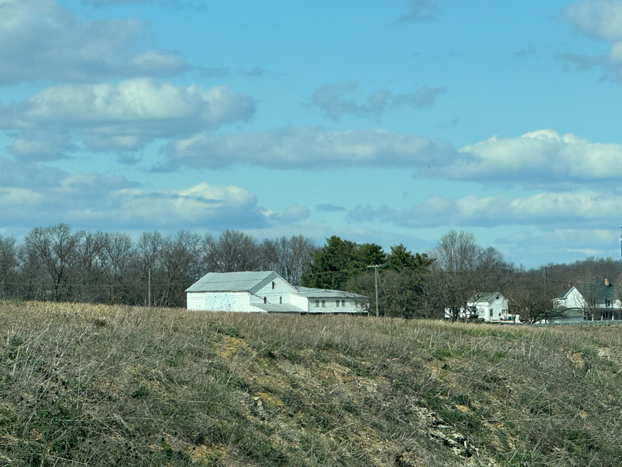 white-farm-buildings-dormant-field-rural-landscape