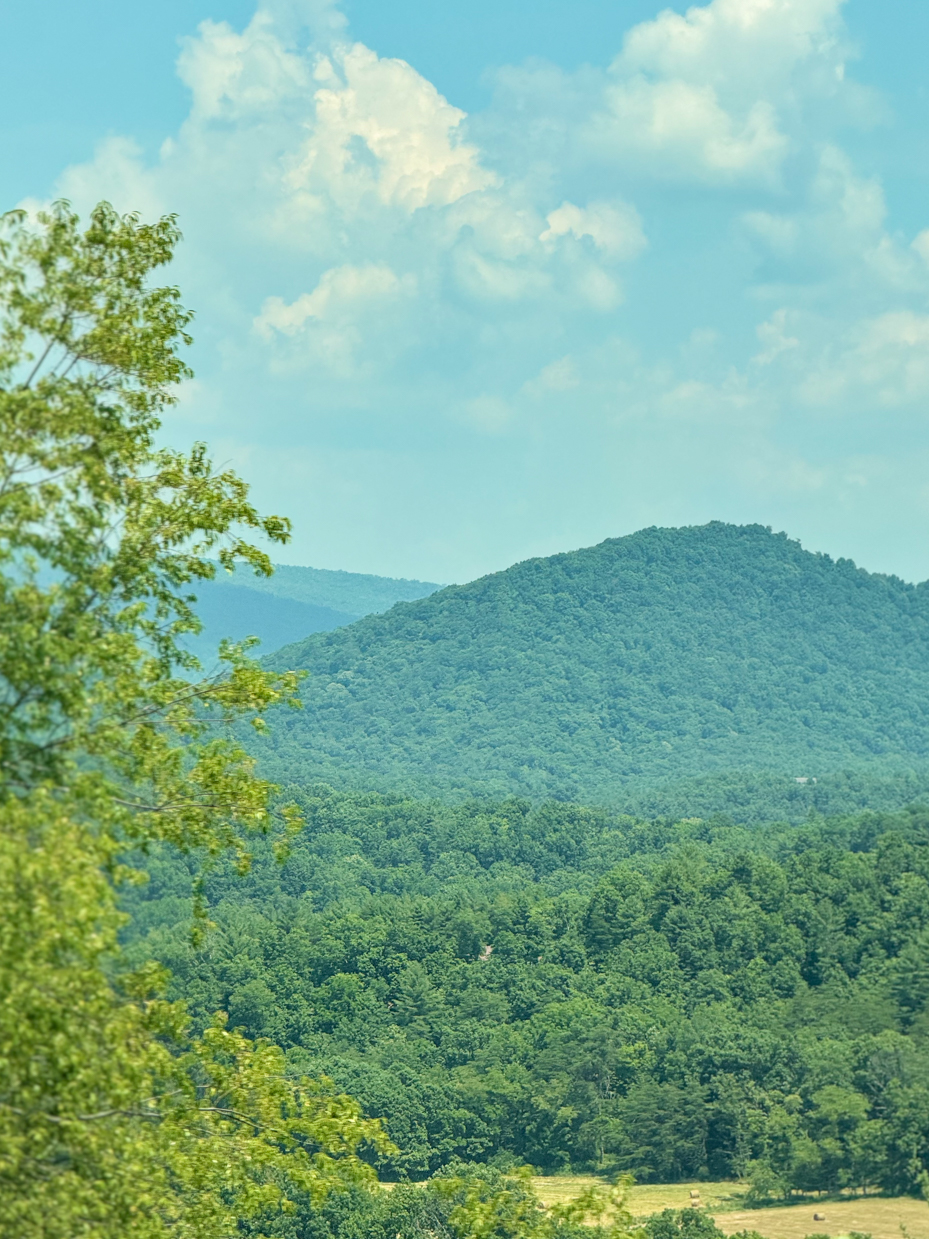 lush-green-forested-mountains-under-blue-cloudy-sky-scenic-overlook-royalty-free-photo