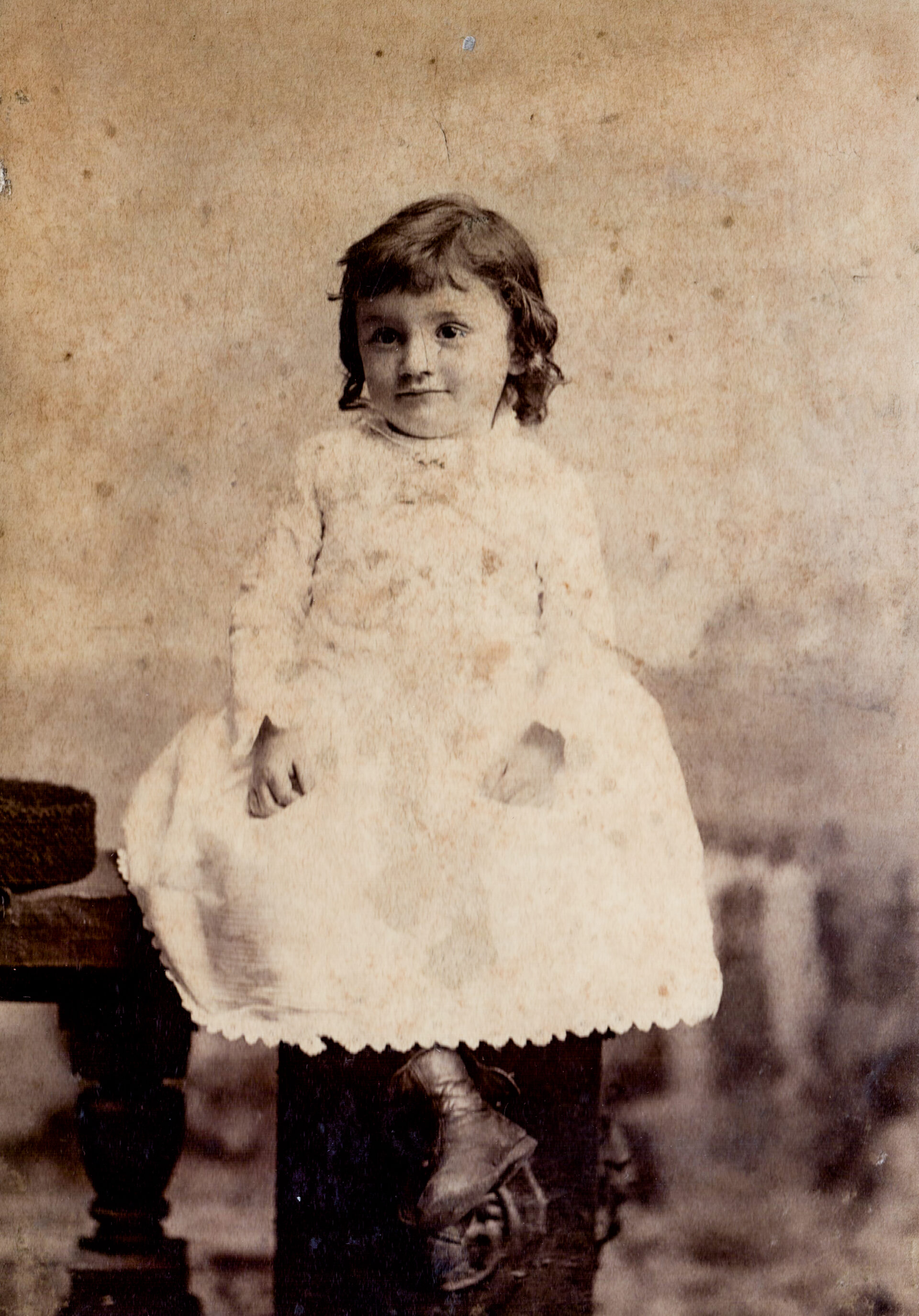 antique-portrait-of-a-young-child-in-victorian-dress-sitting-on-a-table