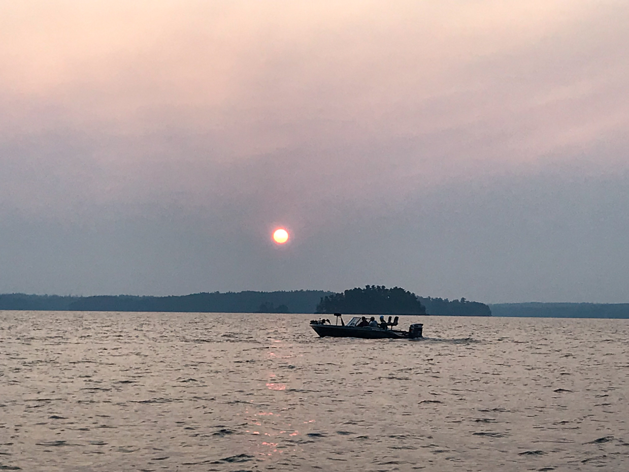 boat-at-sunset-on-tranquil-lake-with-silhouetted-island-peaceful-evening-on-the-water