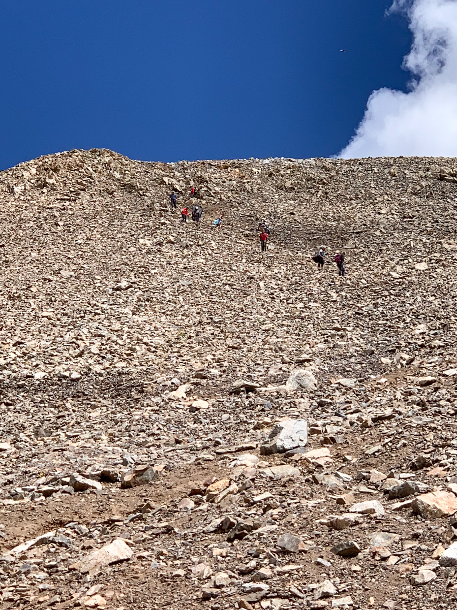 group-of-hikers-climbing-rocky-mountain-slope-under-a-clear-blue-sky-adventure-and-outdoor-exploration