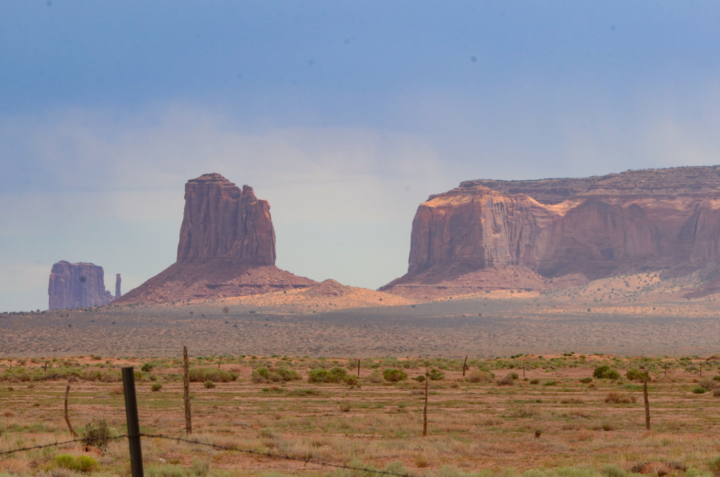 majestic-monument-valley-mesas-towering-over-barren-desert-scrubland-with-rustic-fence-line