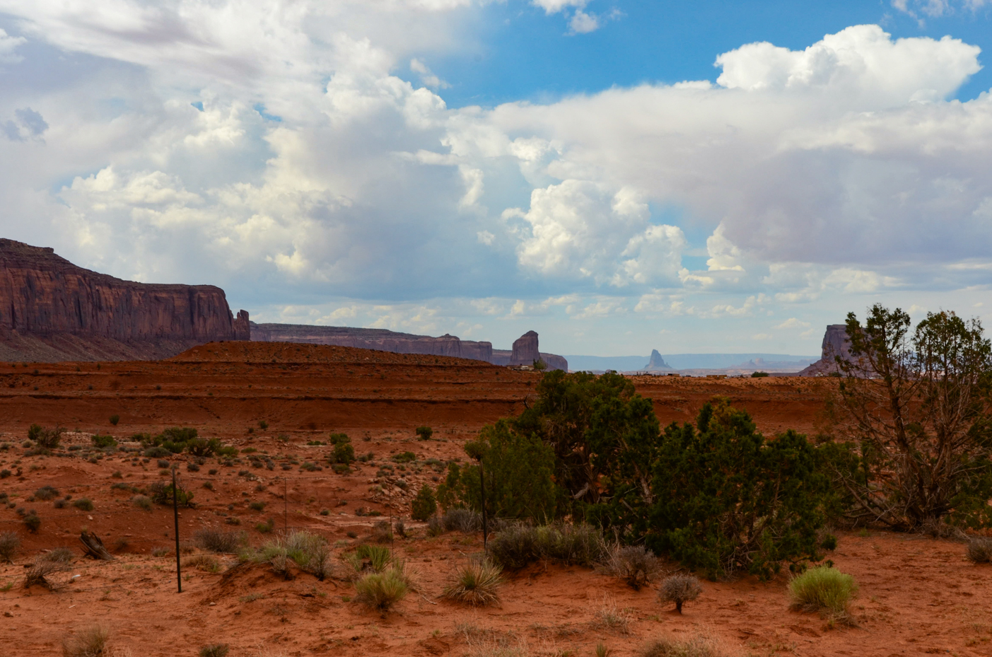 rugged-monument-valley-buttes-rising-above-desert-scrub-under-billowing-cloud-filled-sky