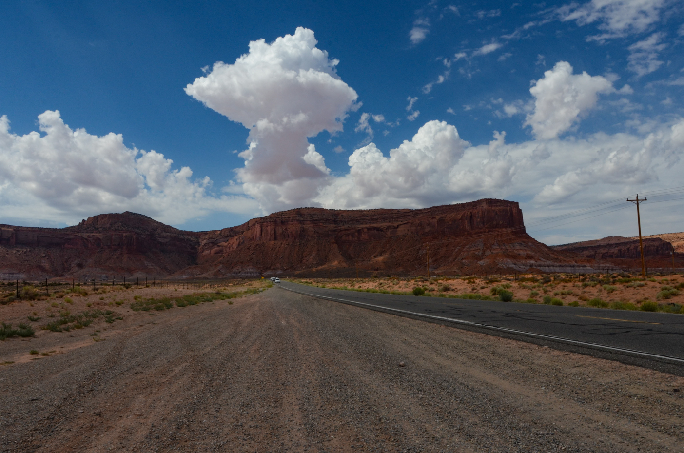 rugged-monument-valley-mesas-looming-over-lonely-desert-highway-under-billowing-clouds