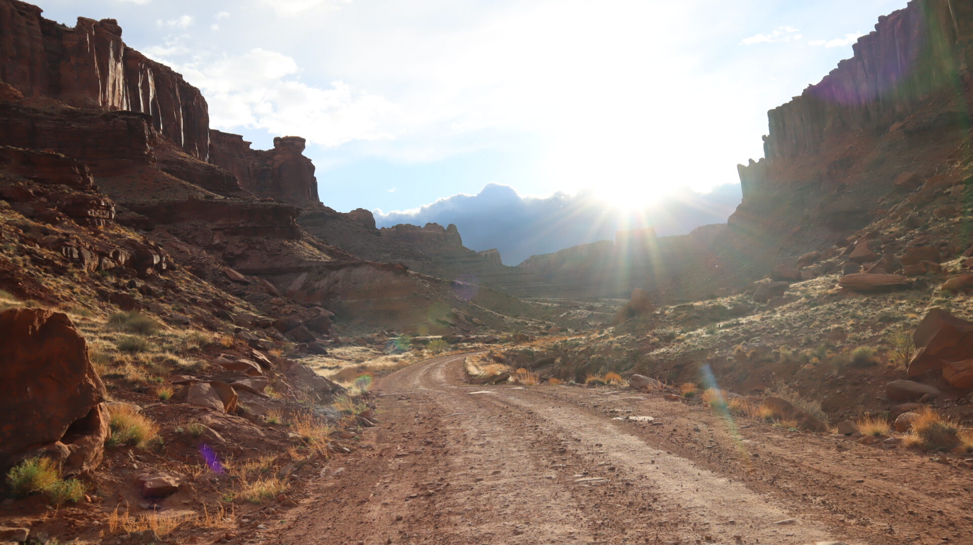 sunlit-desert-canyon-with-winding-dirt-road-and-red-rock-formation