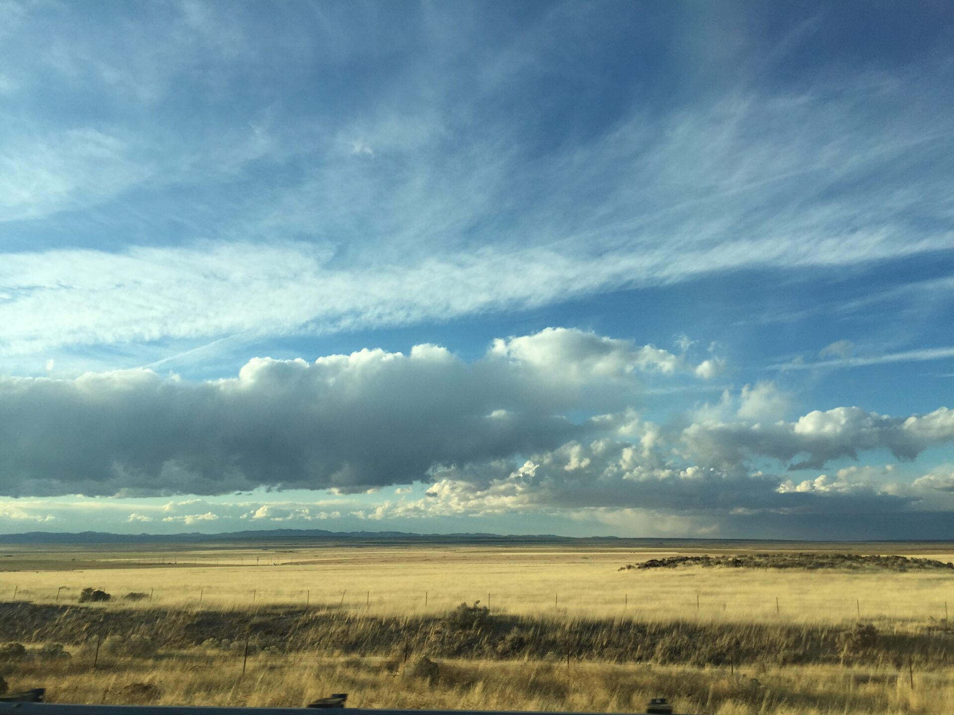 vast-open-prairie-with-cloudy-blue-sky-and-distant-mountains